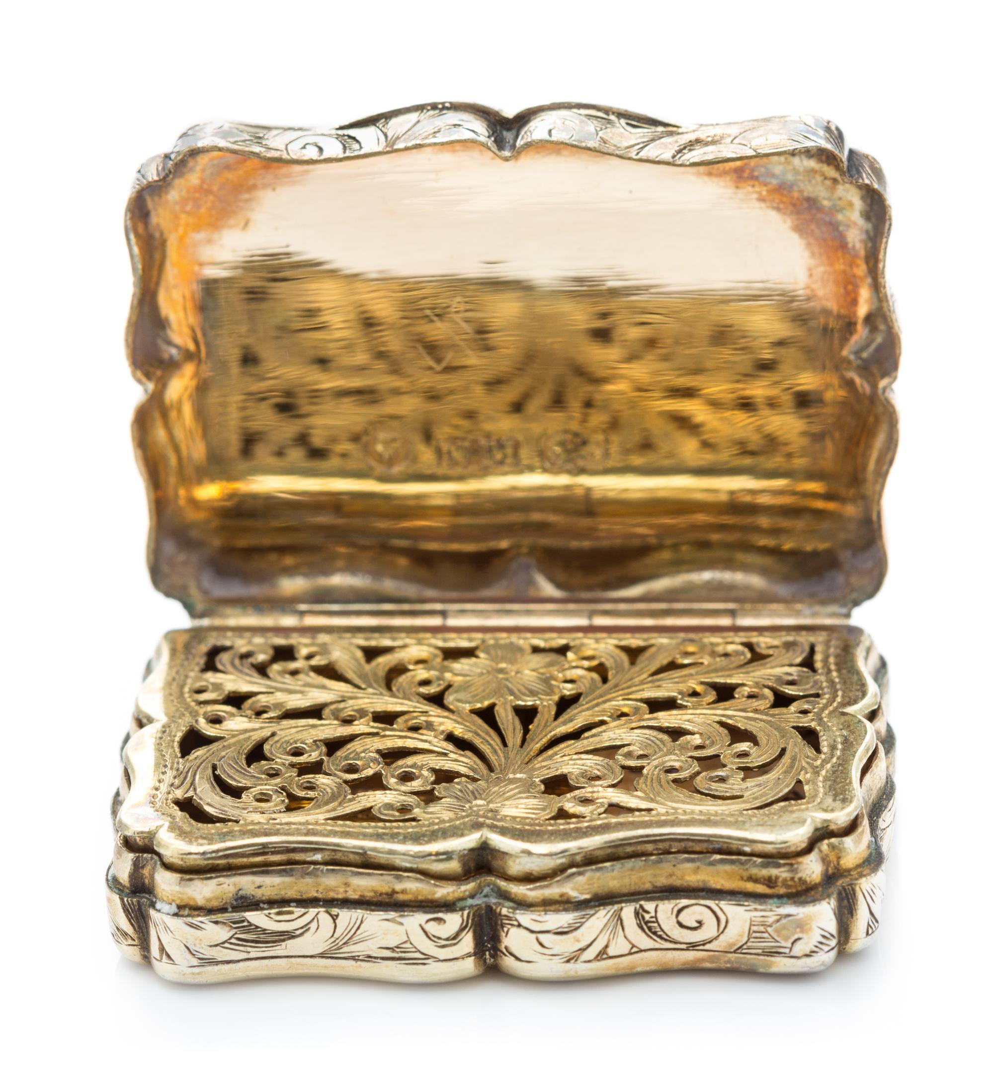A Victorian Silver-Gilt Vinaigrette, Nathaniel Mills, Birmingham, 1843, the case decorated with foliate volutes, the lid centered by a