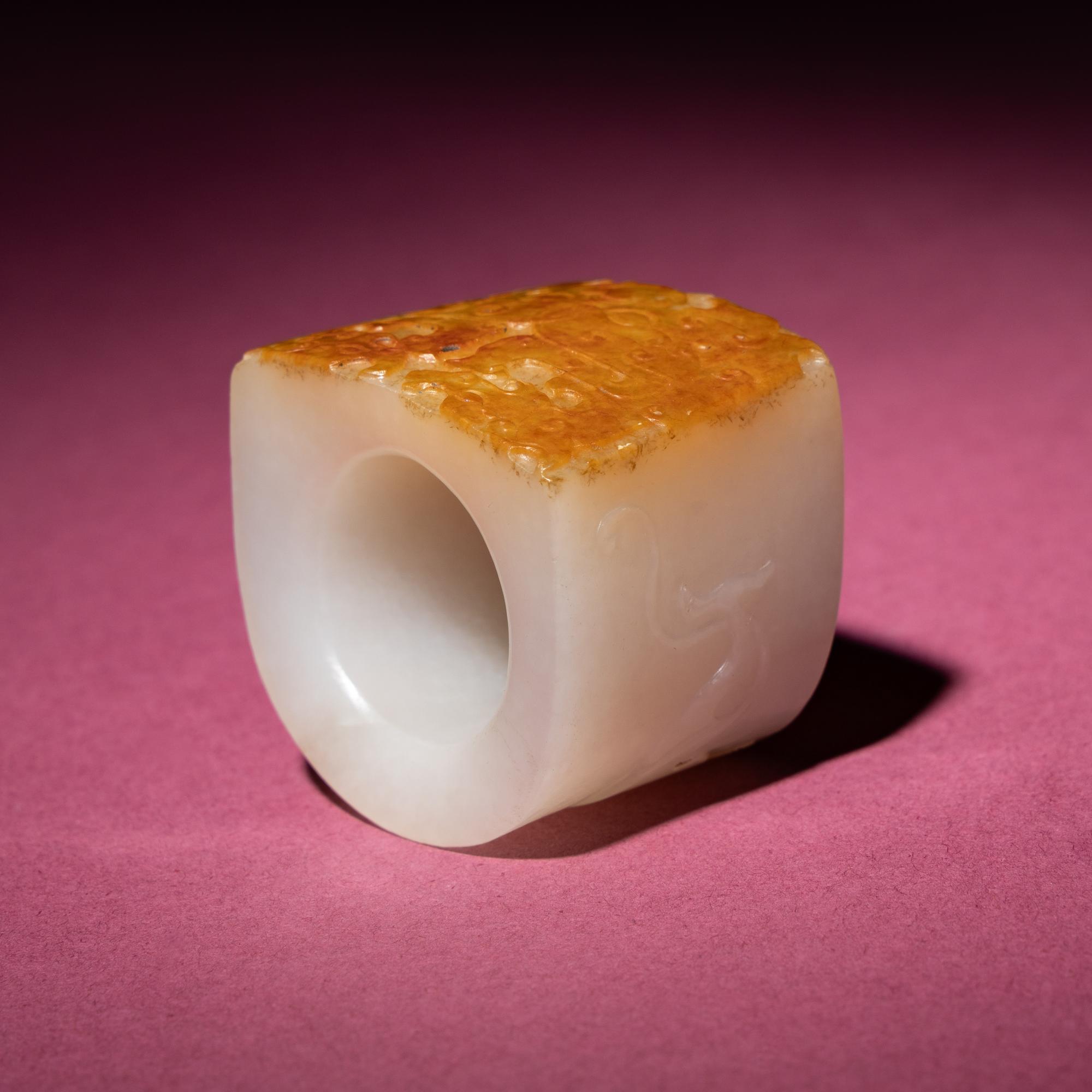 A Chinese Russet and White Jade 'Taotie and Chilong' Archer's Ring, 18th Century — 清中期 白玉留皮饕餮螭龍紋扳指