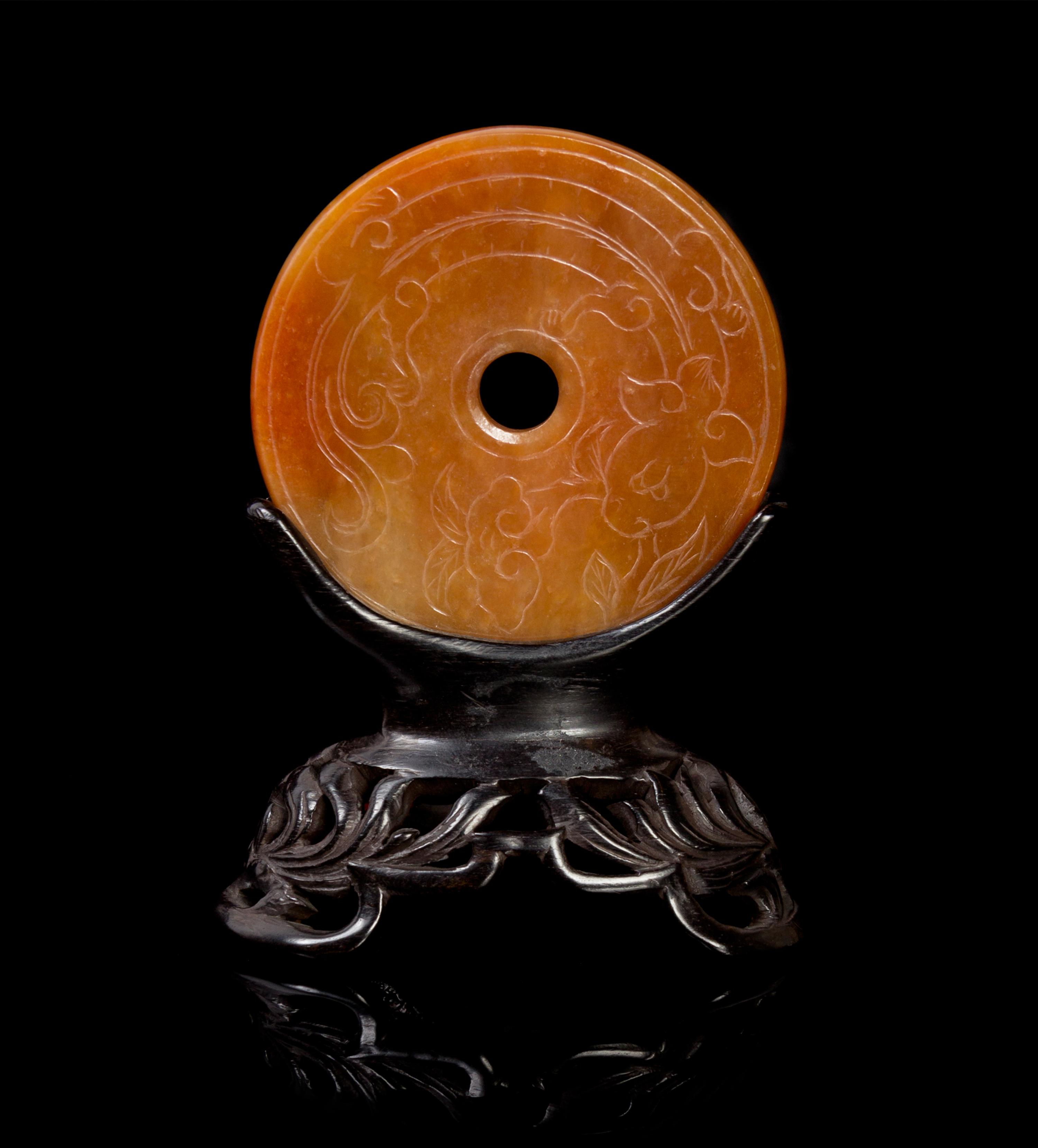 A Chinese Red Jadeite Bi Disk Mounted in Carved Wood Stand LATE 19TH/EARLY 20TH CENTURY — LATE 19TH/EARLY 20TH CENTURY
