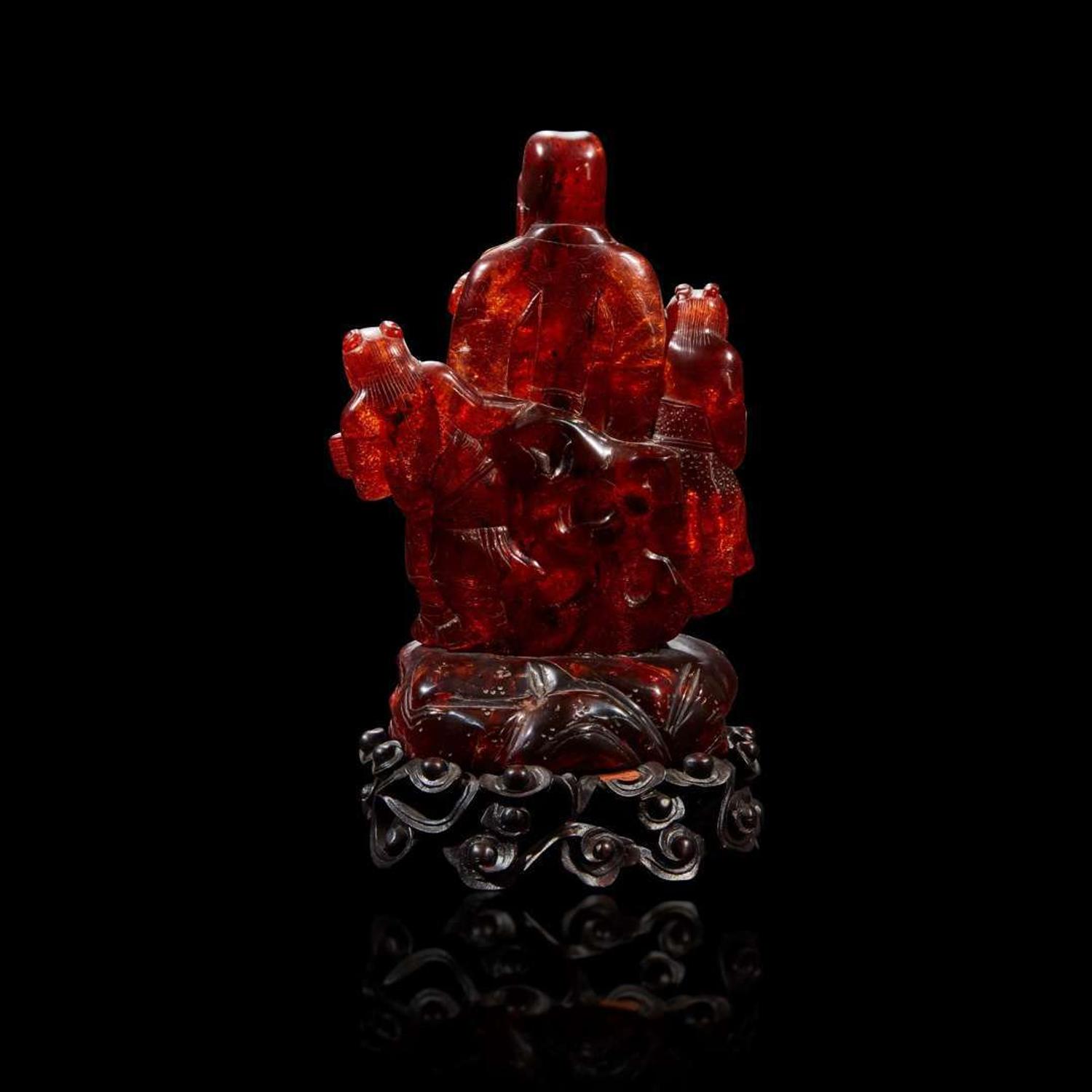 A Chinese carved amber figure of a sage and acolytes