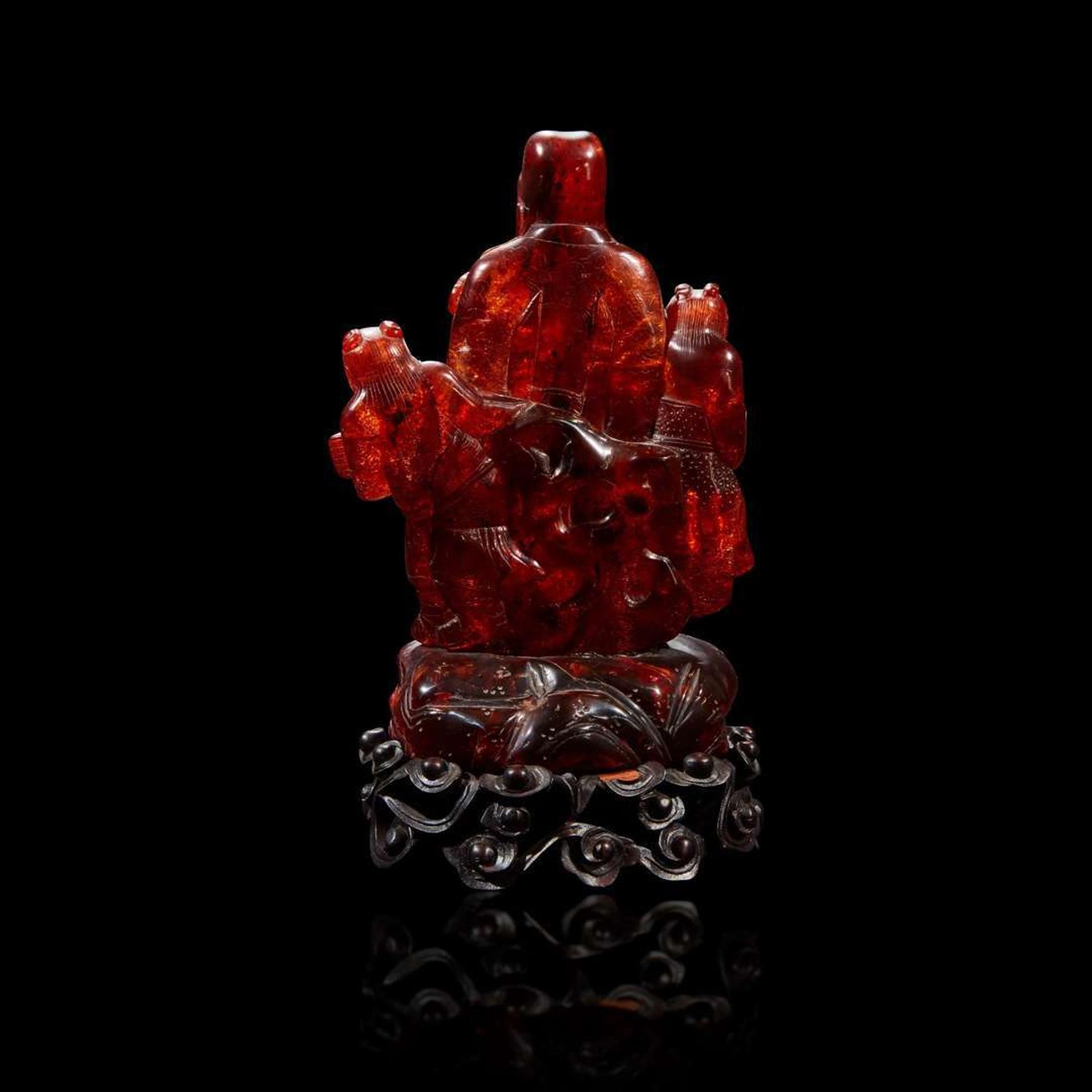 A Chinese carved amber figure of a sage and acolytes