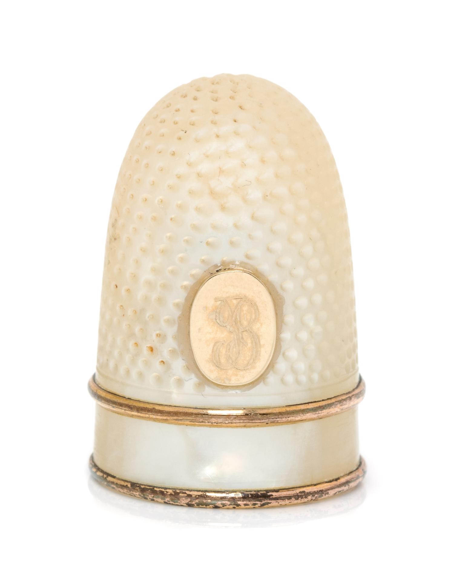 A French Palais Royal Mother-of-Pearl Thimble, Late 18th/Early 19th Century, the domed body with an applied gilt metal oval plaque bear
