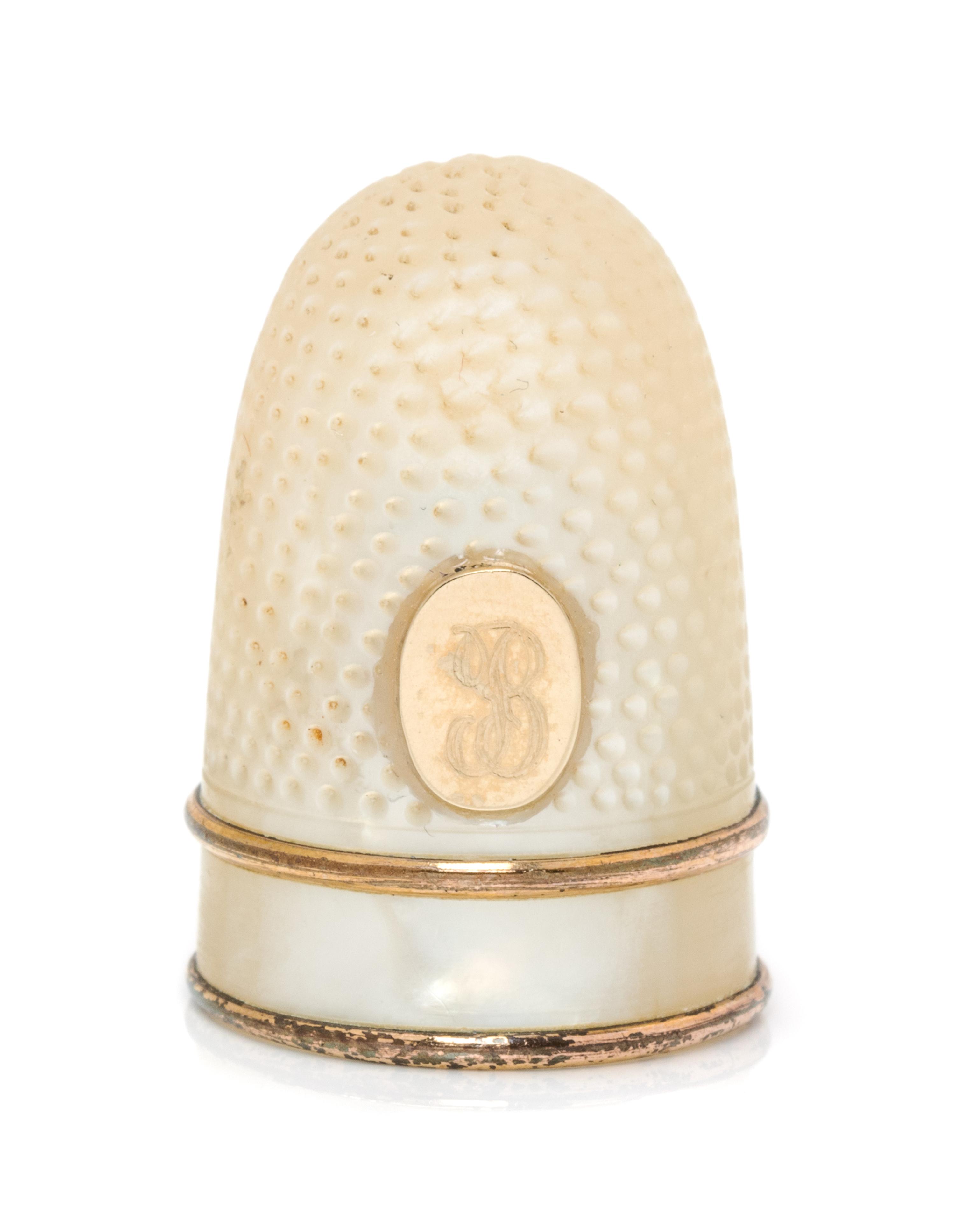 A French Palais Royal Mother-of-Pearl Thimble, Late 18th/Early 19th Century, the domed body with an applied gilt metal oval plaque bear