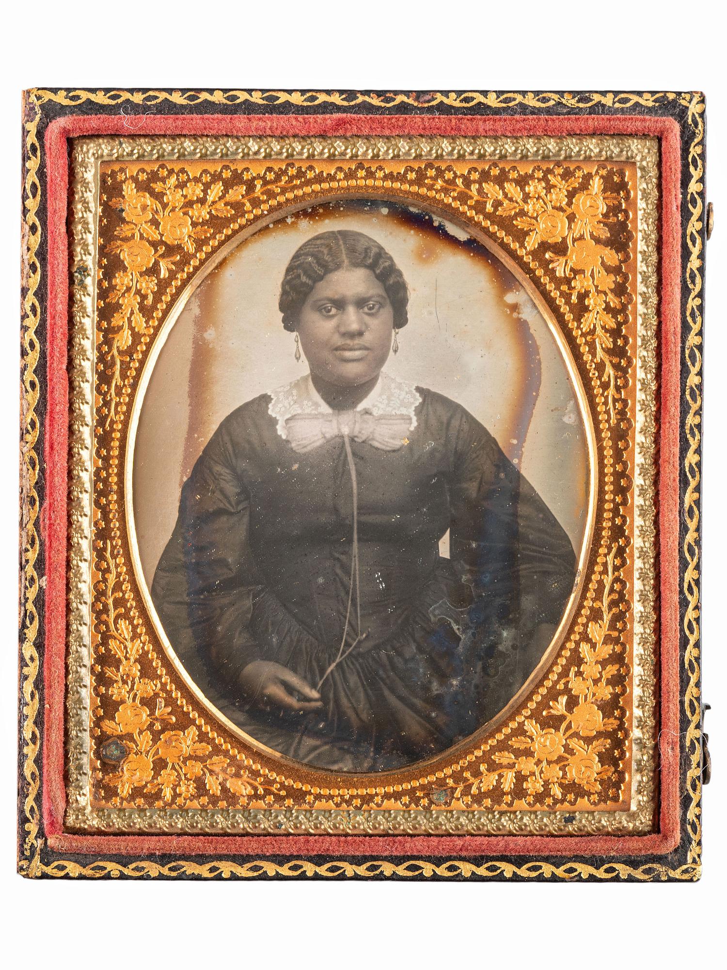 [EARLY PHOTOGRAPHY-AFRICAN AMERICANA]. Sixth plate daguerreotype portrait of subject identified as "Grandma Binx" with braided hairwork heart.