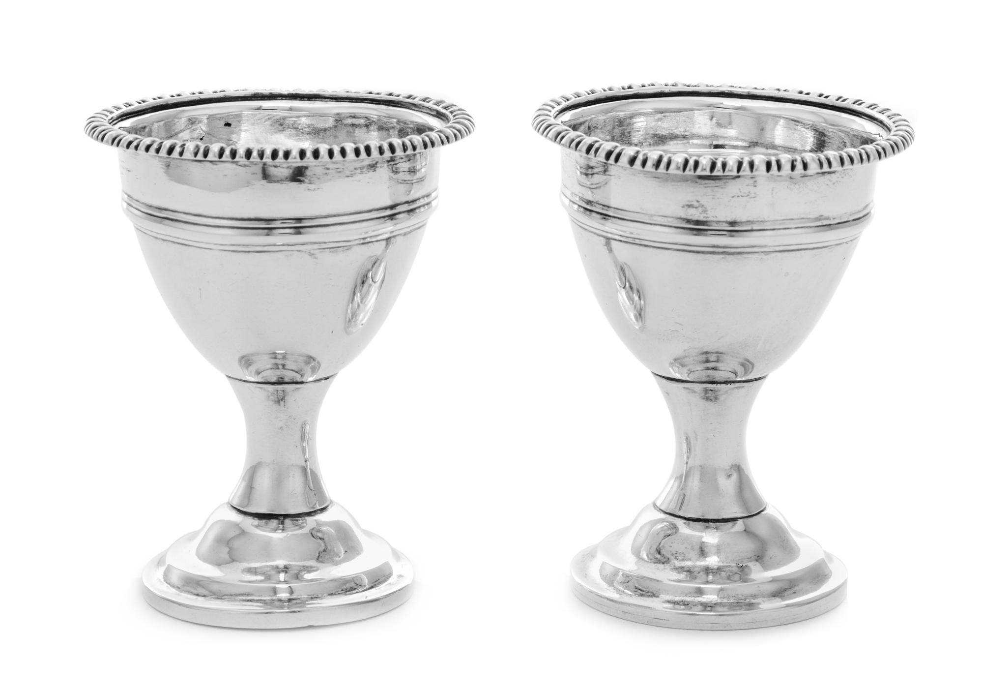 A Pair of Irish George III Silver Egg Cups, Maker's Mark Obscured, Dublin, 18th Century, each having a gadrooned rim and a banded body.