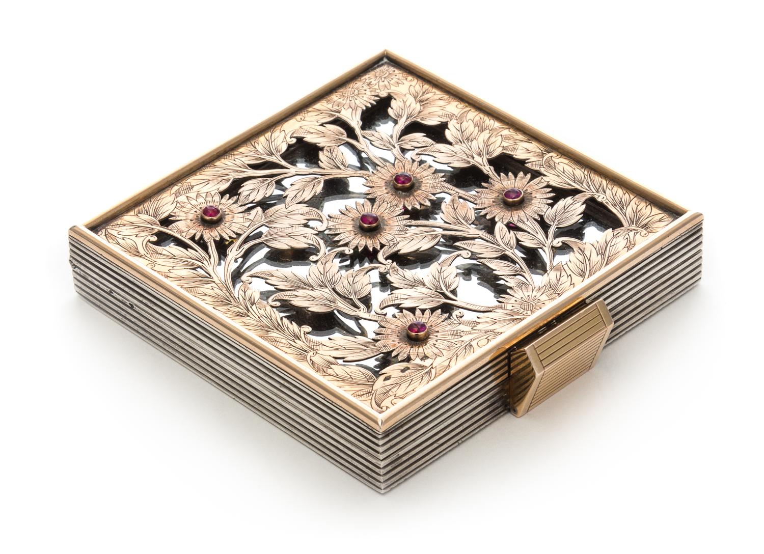 A French Silver, Rose Gold and Ruby Compact, Boucheron, Paris, 1935, the pierced and engraved cover depicting flowers and set with five