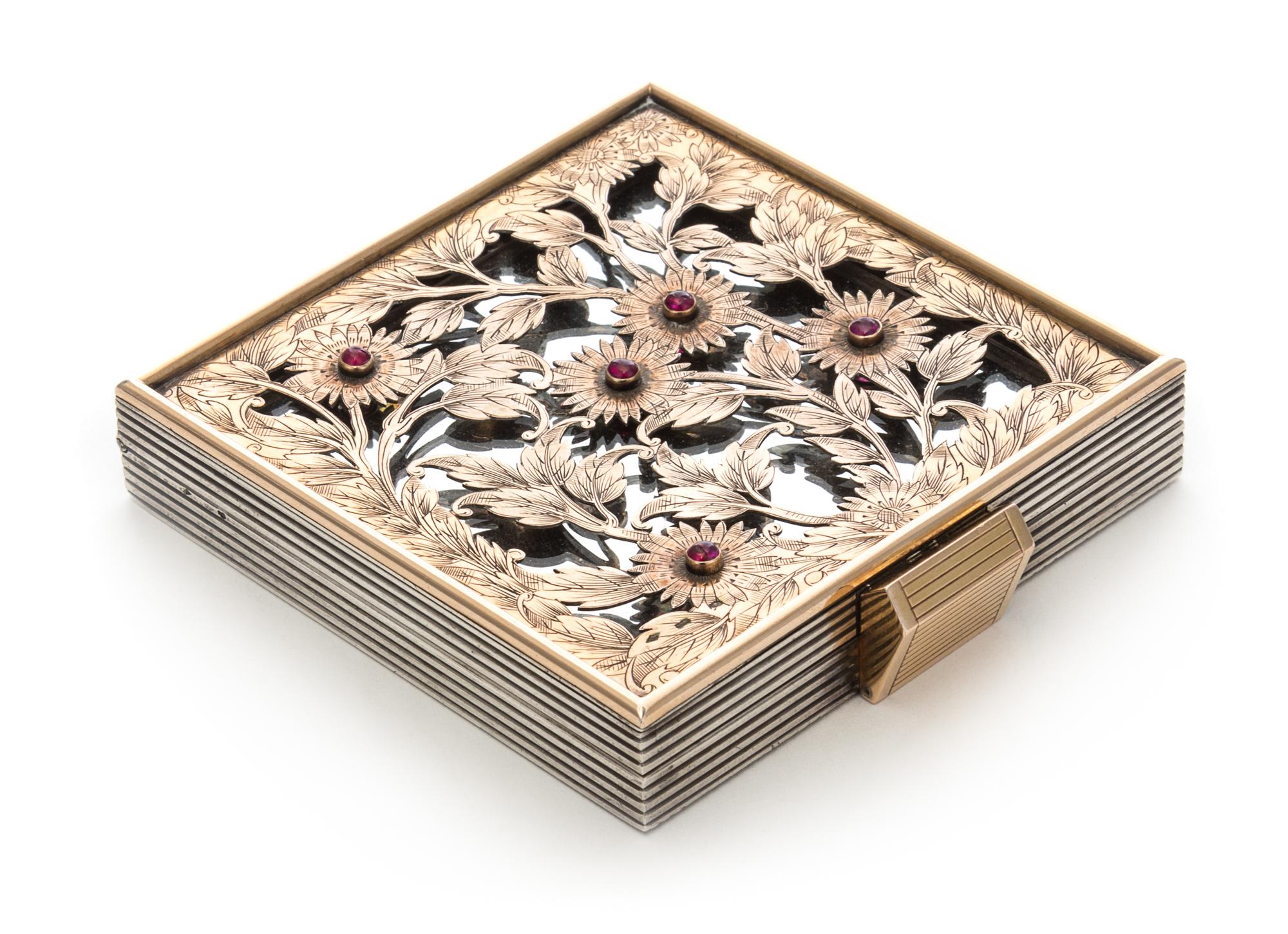 A French Silver, Rose Gold and Ruby Compact, Boucheron, Paris, 1935, the pierced and engraved cover depicting flowers and set with five