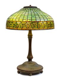 A Tiffany Studios Leaded Favrile Glass and Bronze Greek Key Table Lamp Height 23 x diameter of shade 16 inches.