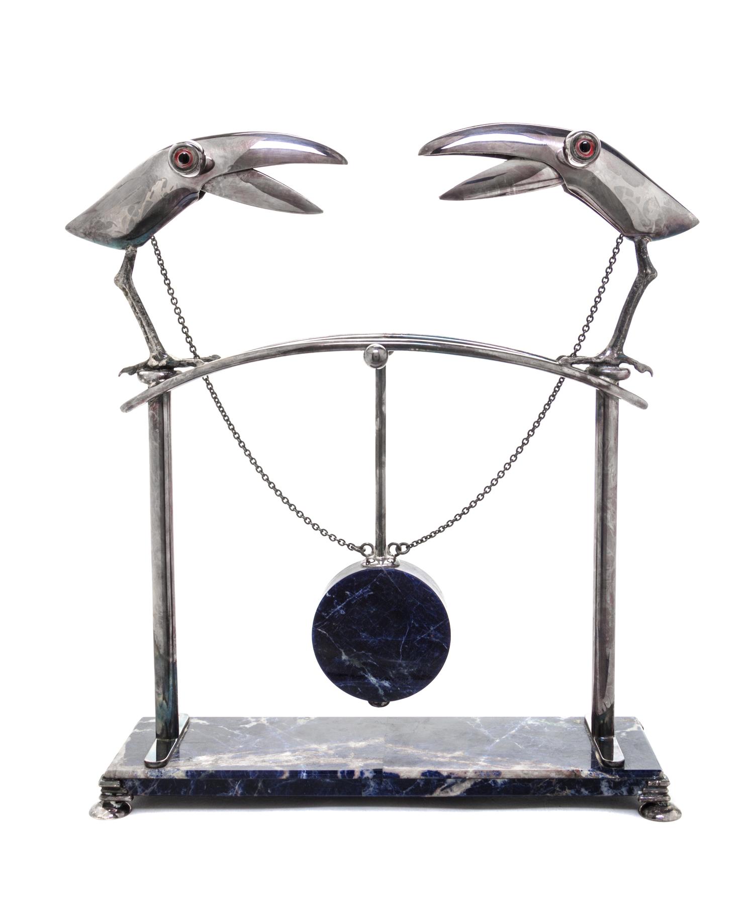 A Continental Silver and Marble Sculpture, 1989, depicting two stylized toucans joined by chains to a central pendulum, on a rectangula