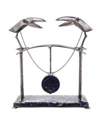 A Continental Silver and Marble Sculpture, 1989, depicting two stylized toucans joined by chains to a central pendulum, on a rectangula