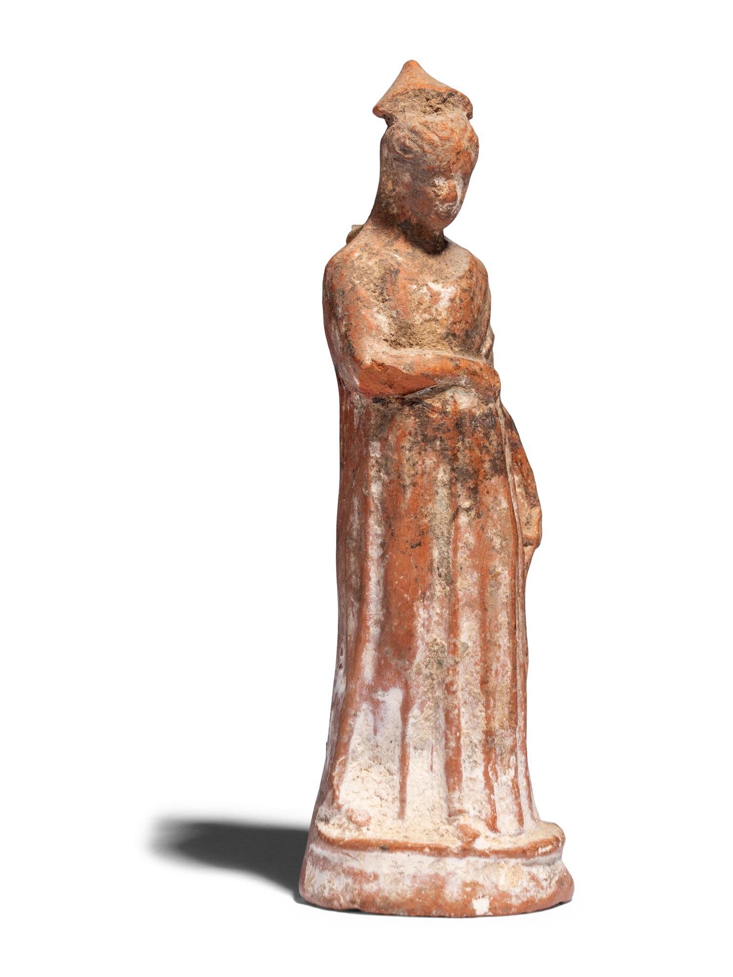 A Greek Terracotta Draped Female Figure with a Pilos