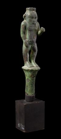 An Egyptian Bronze Bes Standing on a Papyrus Umbel Height 7 inches. — THIRD INTERMEDIATE PERIOD, DYNASTY 21-22, 1070-712 B.C.E.