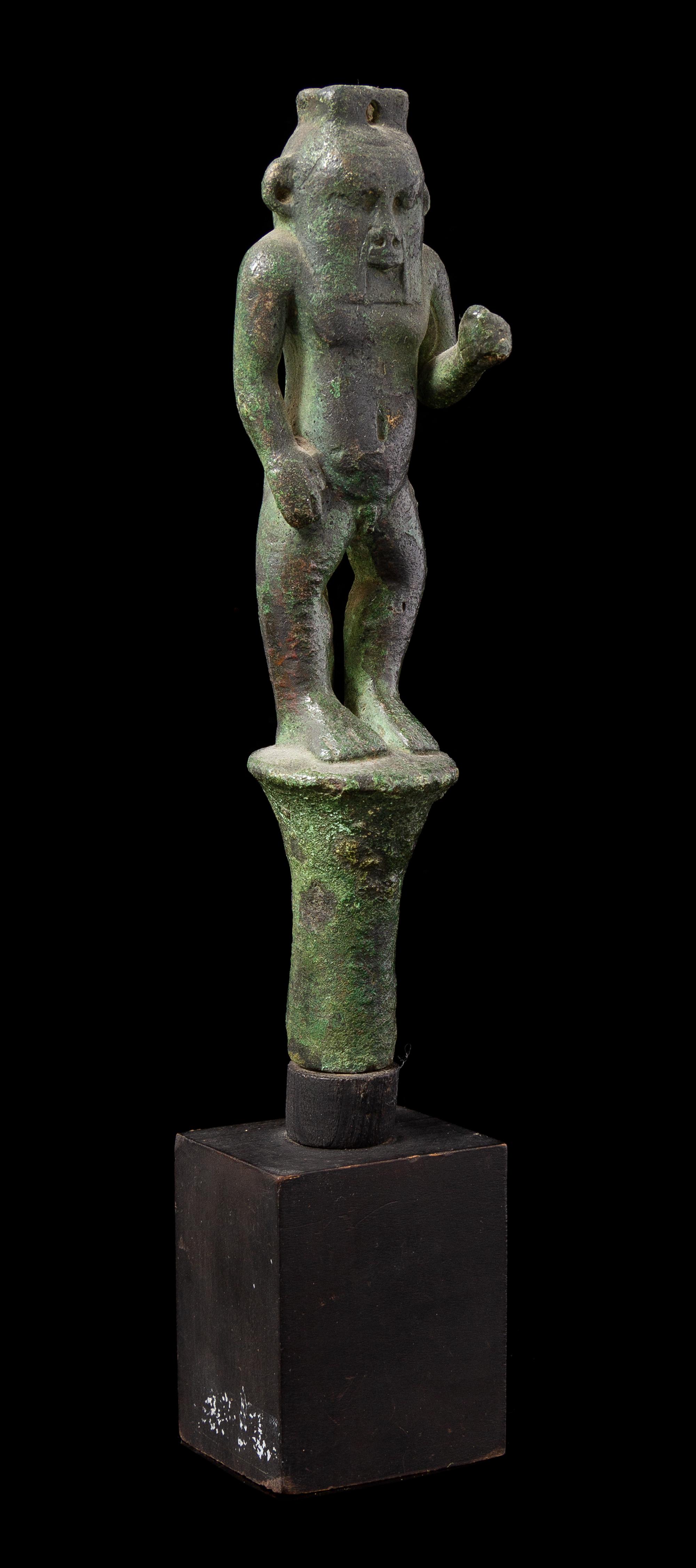 An Egyptian Bronze Bes Standing on a Papyrus Umbel Height 7 inches. — THIRD INTERMEDIATE PERIOD, DYNASTY 21-22, 1070-712 B.C.E.