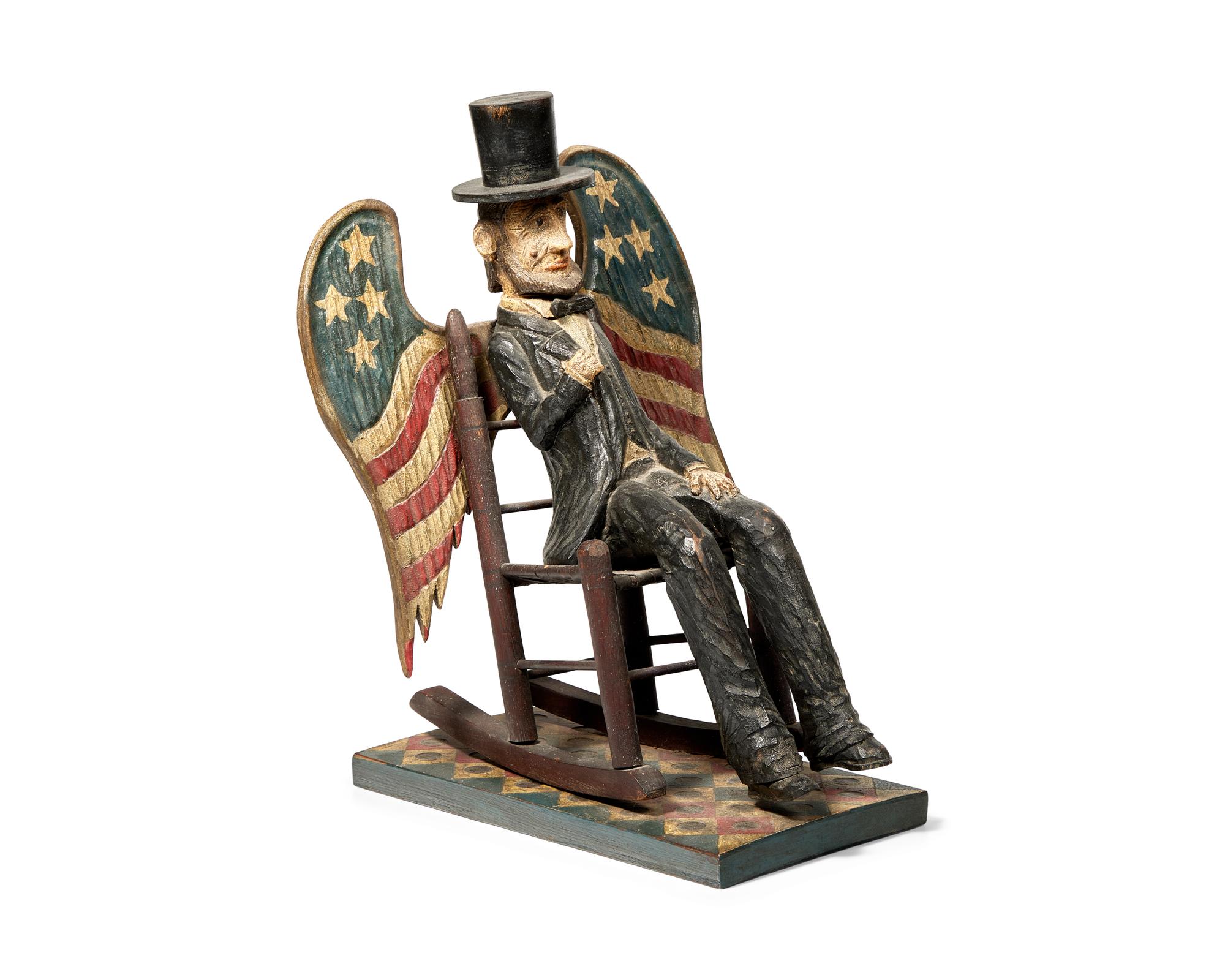 A Carved And Painted Figure Of A Seated Abraham Lincoln With Wings Painted As American Flag