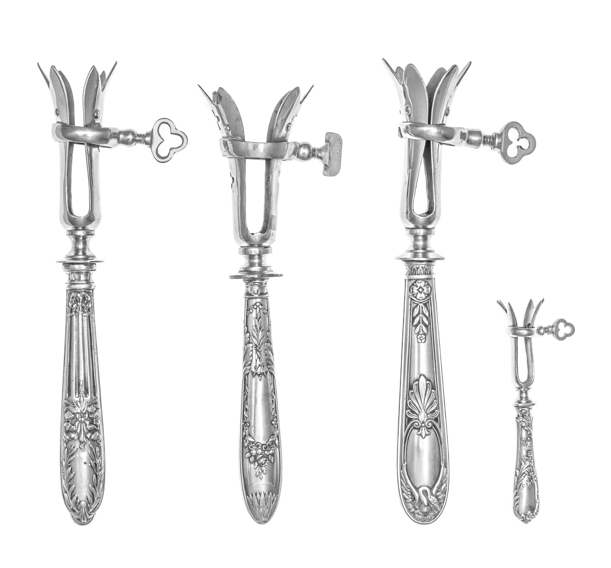 A Group of Four French Silver Bone Holders, various makers, the handles worked to show floral and ribbon swags, comprising three standa