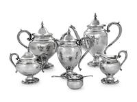 comprising a coffee pot, teapot, chocolate pot, creamer, covered sugar, tea strainer and cup, 7 items total.