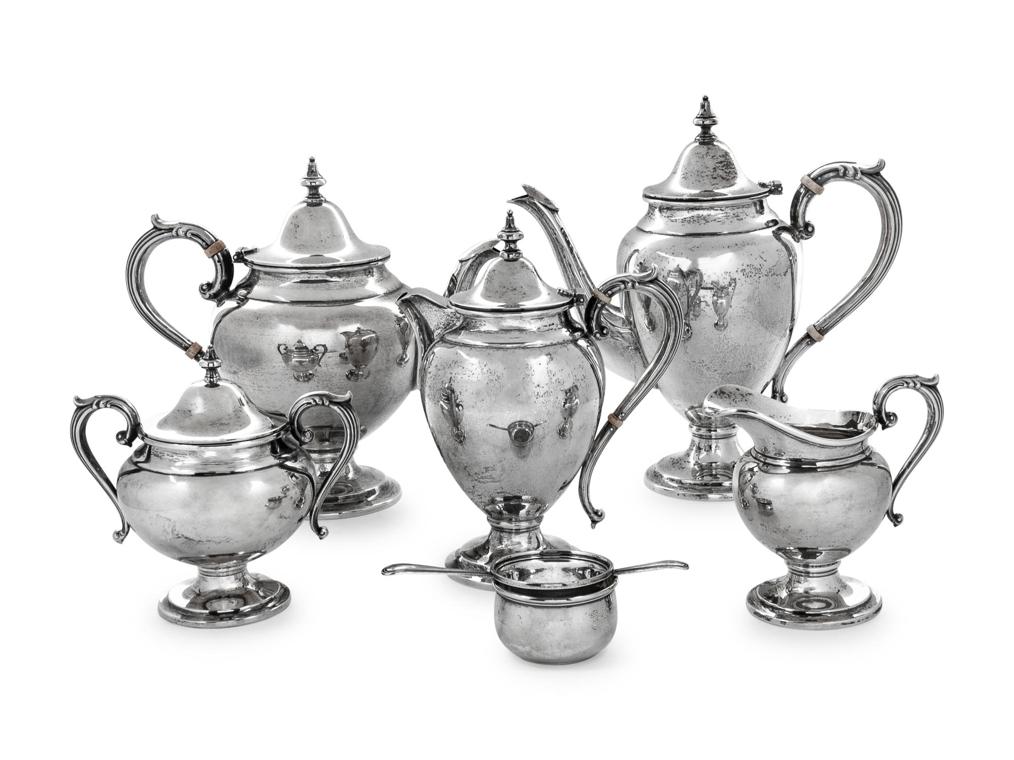 comprising a coffee pot, teapot, chocolate pot, creamer, covered sugar, tea strainer and cup, 7 items total.