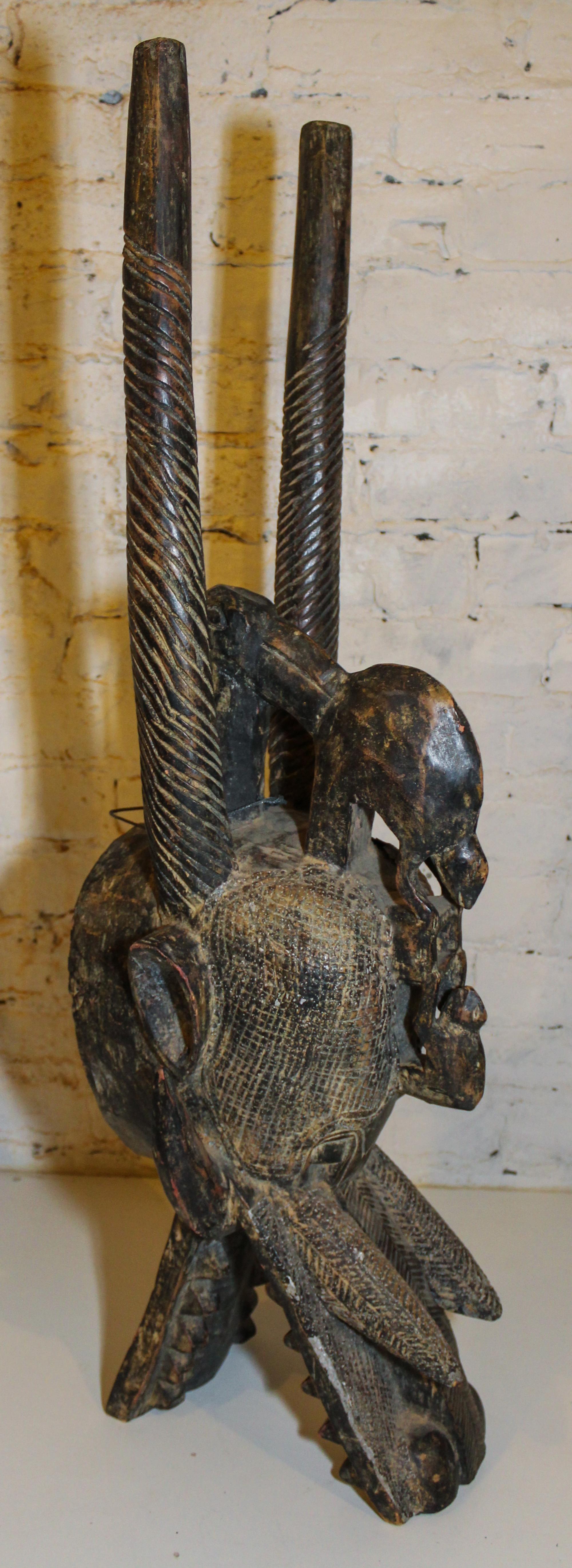 A Senufo Wood and Patinated Metal "Firespitter" Mask Height 35 1/2 inches.