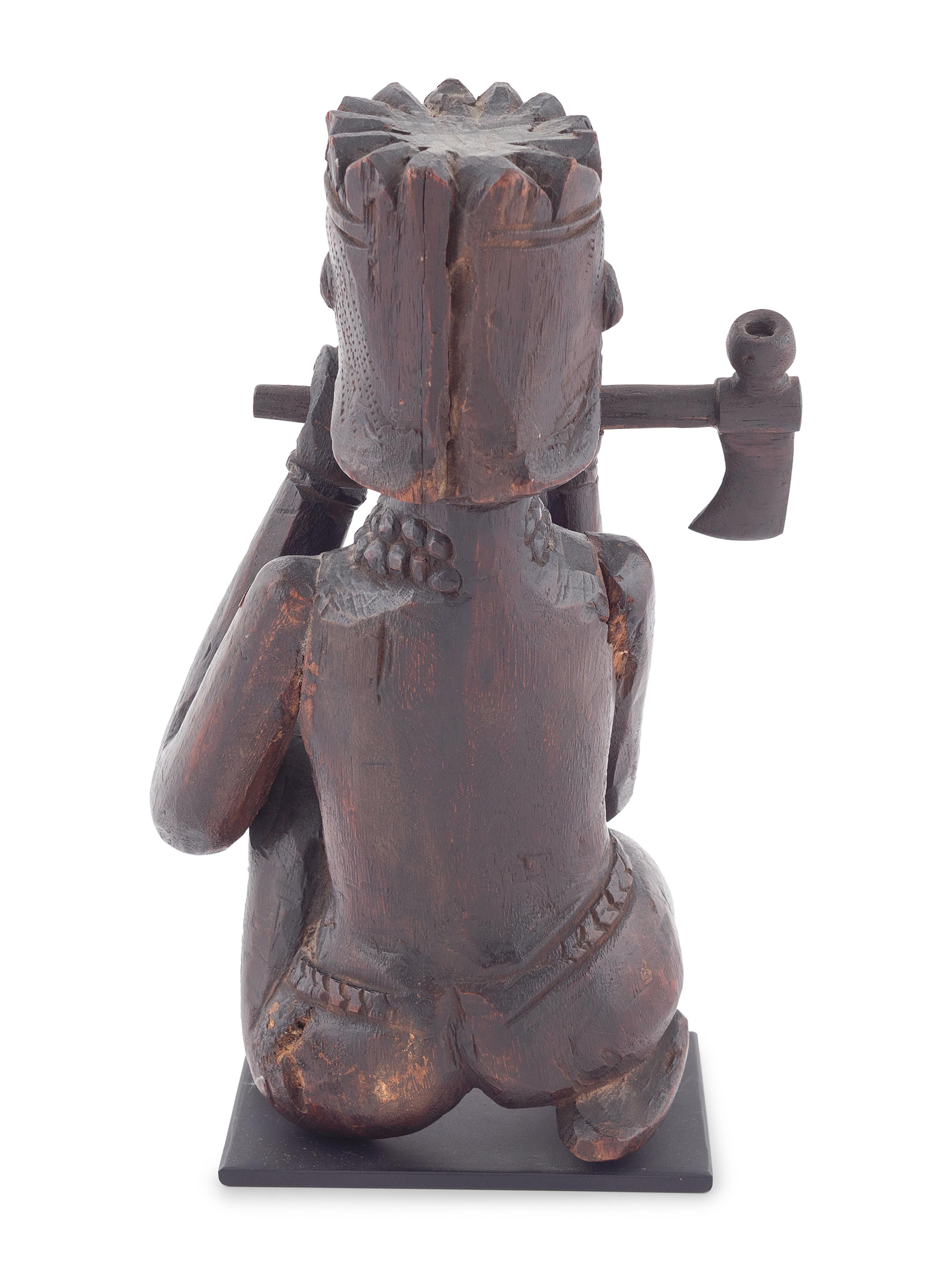 A Seated Folk Art Carved Walnut Indian with Tomahawk