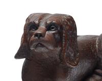 A Carved and Brown- Painted Figure of a Reclining Spaniel