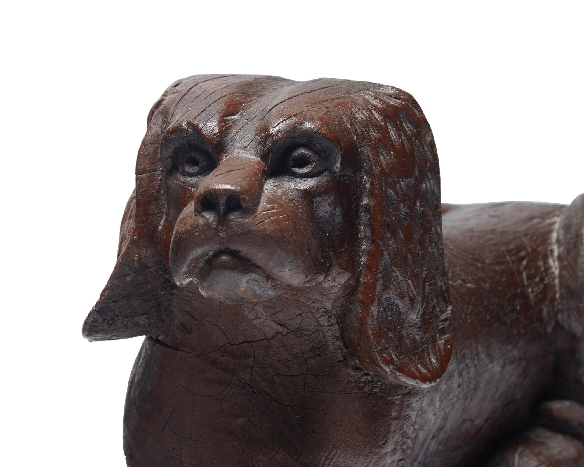 A Carved and Brown- Painted Figure of a Reclining Spaniel