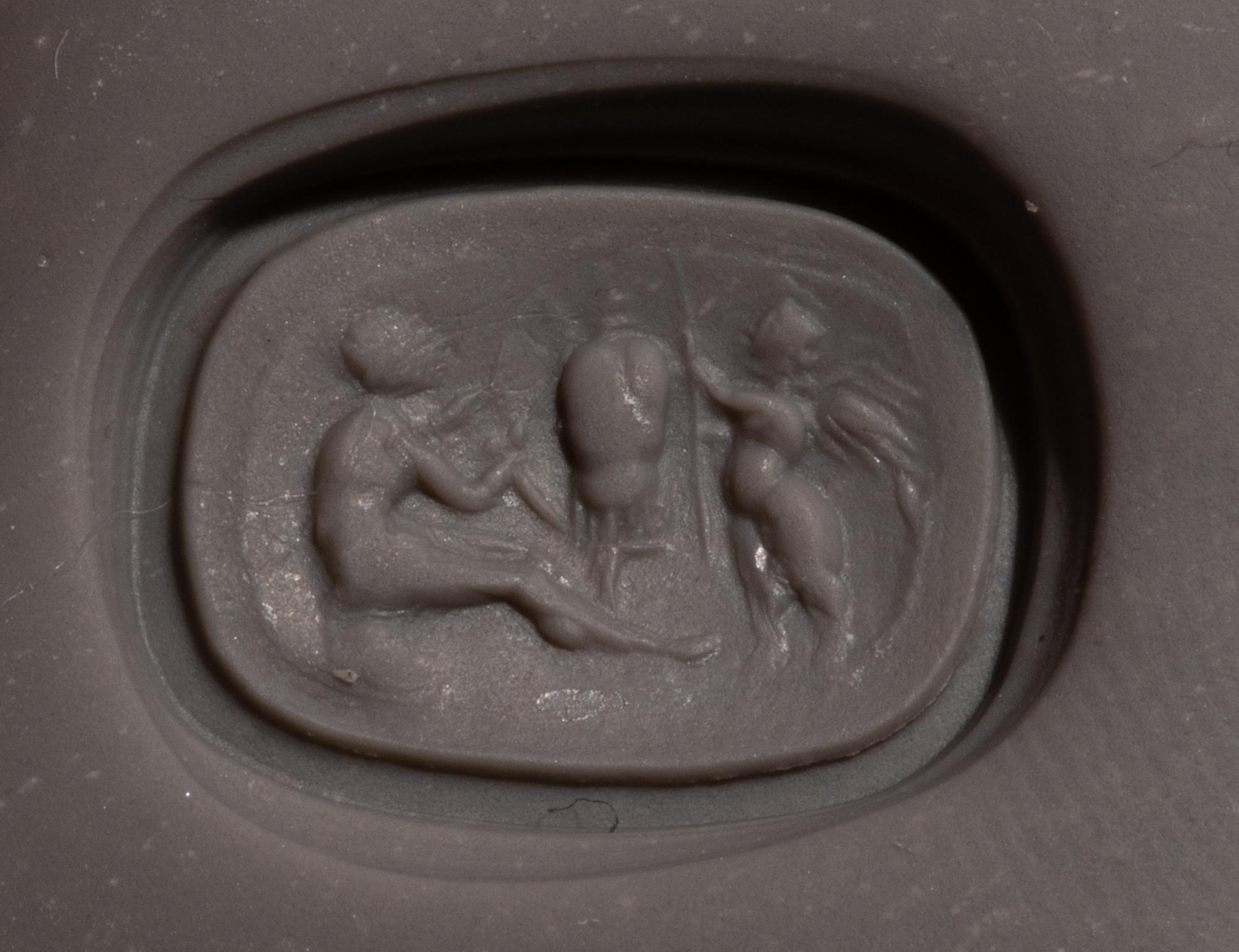 A Roman Carnelian Ring Stone with the God Eros Beside a Tropaion — Set in a gilt-copper ring