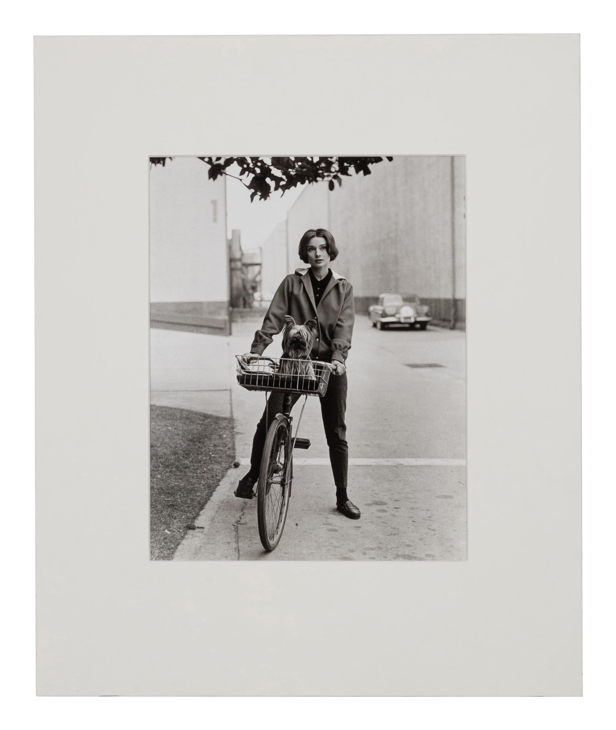 Sid Avery (1918-2002) Audrey Hepburn on her bicycle with her dog "Famous" at Paramount Studios, Los Angeles, CA, 1957