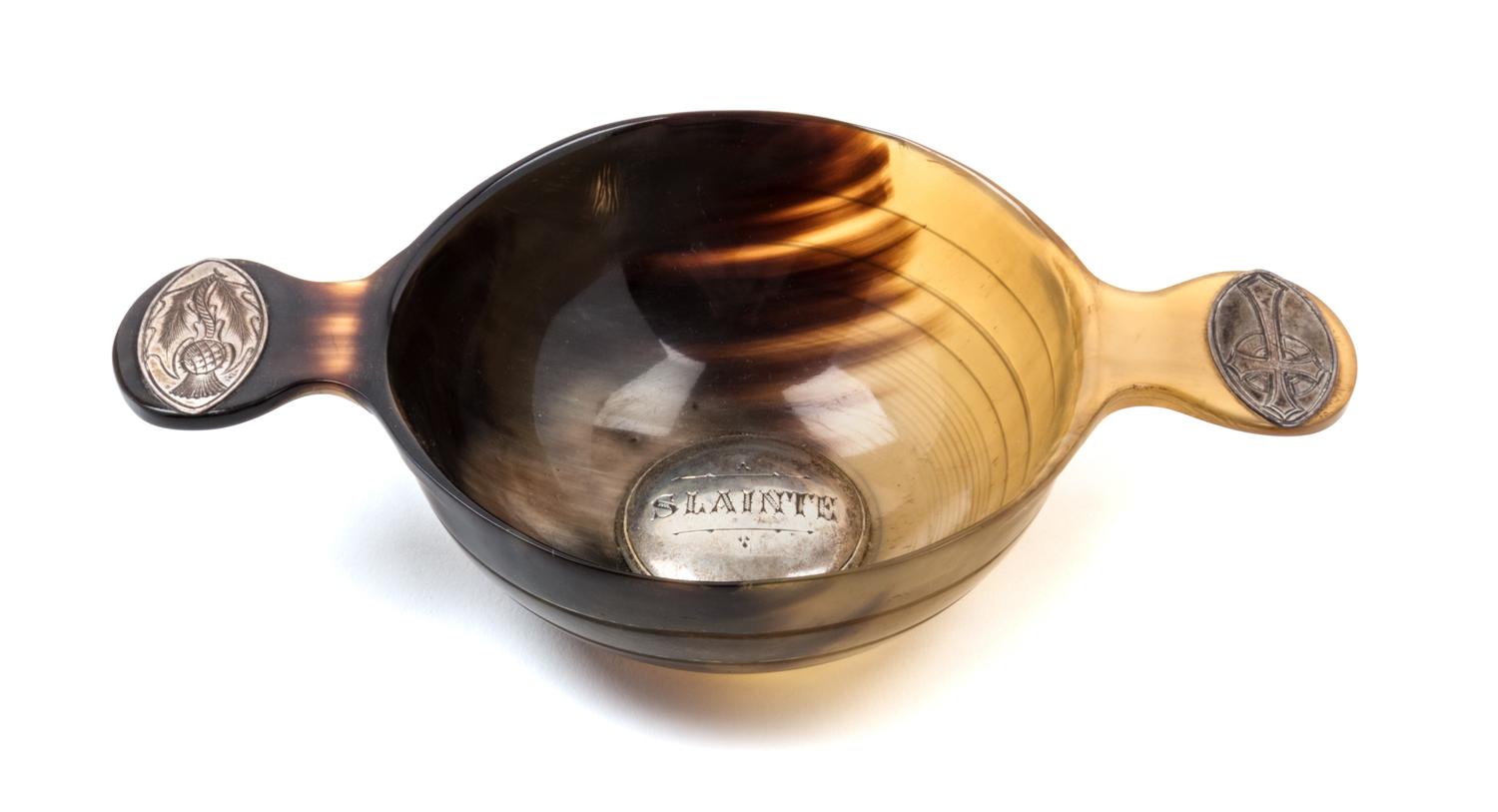 A Scottish Horn Quaich, , of typical form, the bowl centered by a silver medallion engraved Slainte, the handles with inset medallions