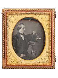 [EARLY PHOTOGRAPHY]. Sixth plate daguerreotype of a photographer posed with an American-made chamfered box camera atop a wooden tripod.