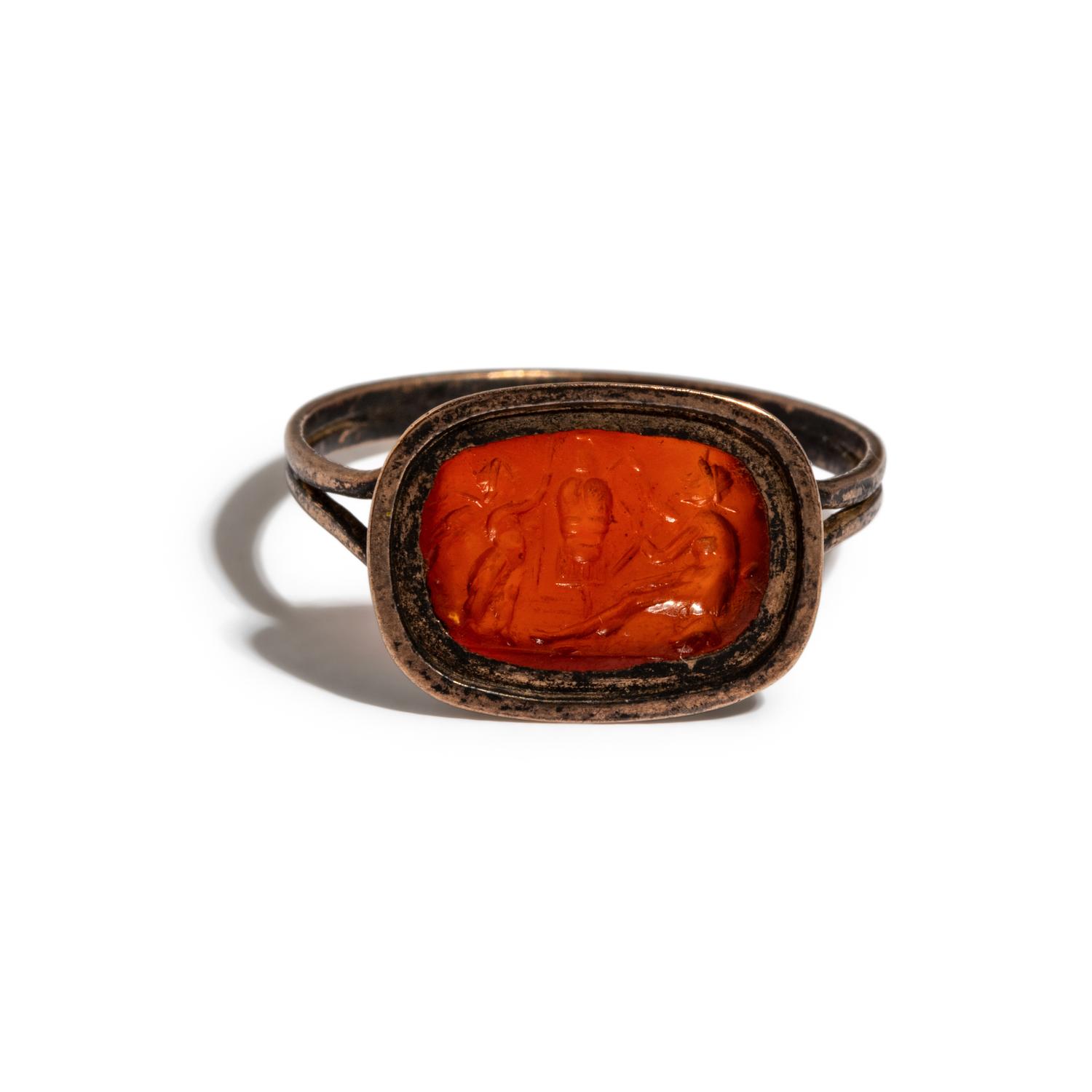 A Roman Carnelian Ring Stone with the God Eros Beside a Tropaion — Set in a gilt-copper ring