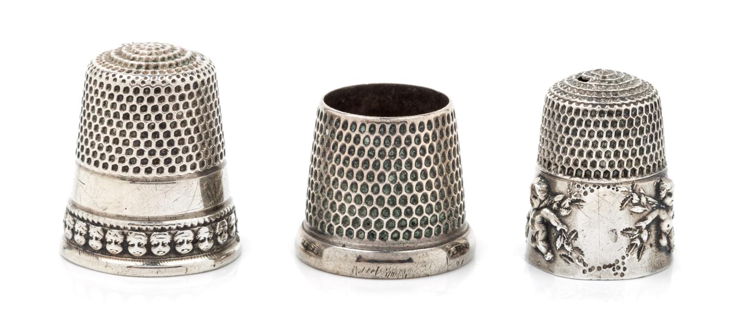 Three American Silver Thimbles, Various Makers, comprising an example with a rim worked to show putti masks, Goldsmith Stear & Co., New