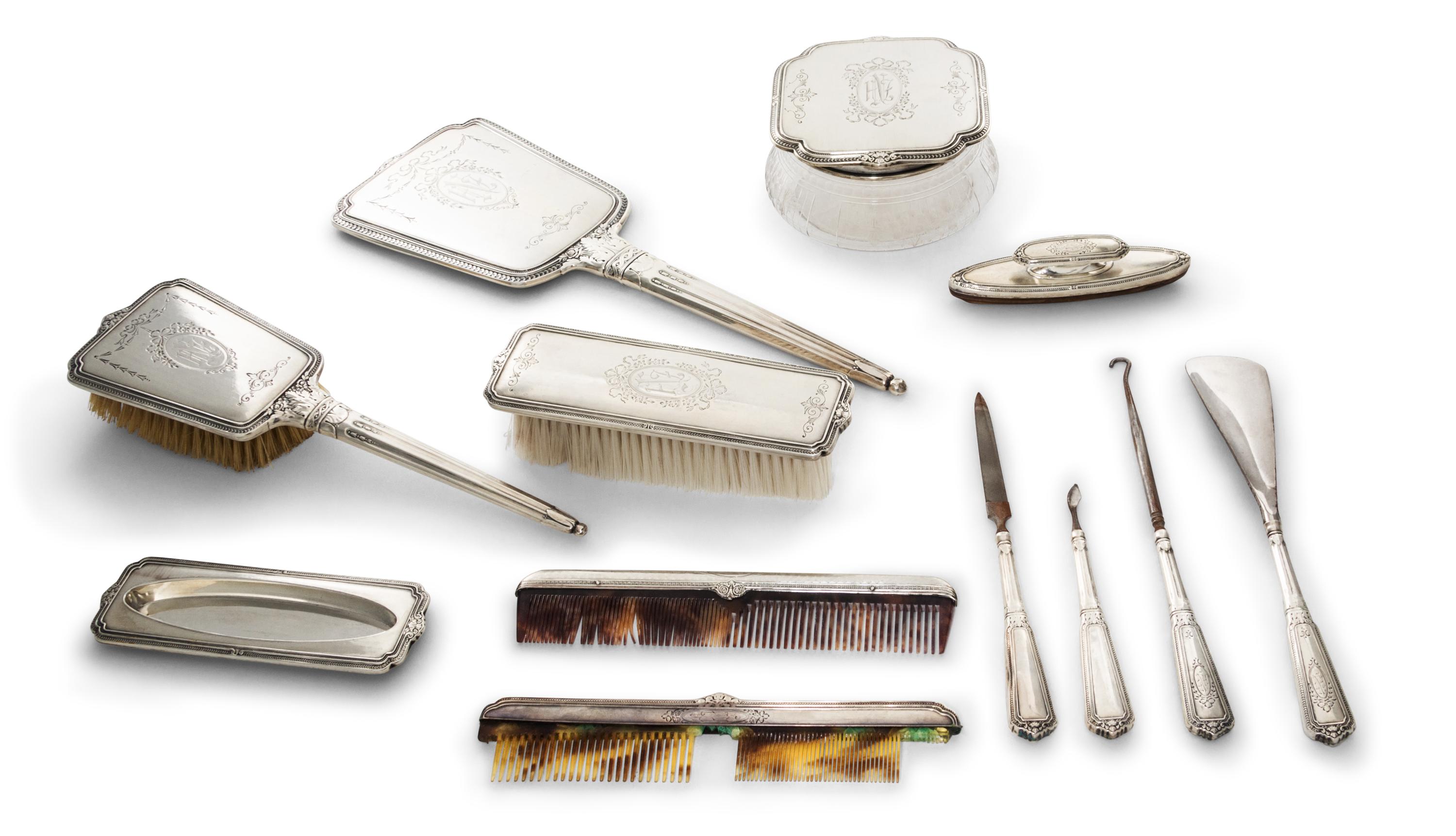 An American Silver Mounted Dresser Set, 20th century, comprising a hand mirror, a glass powder jar with a silver lid, two brushes, two