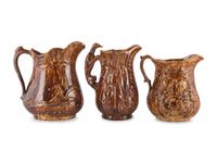 Seven Molded Yellowware Pitchers in Rockingham Glaze