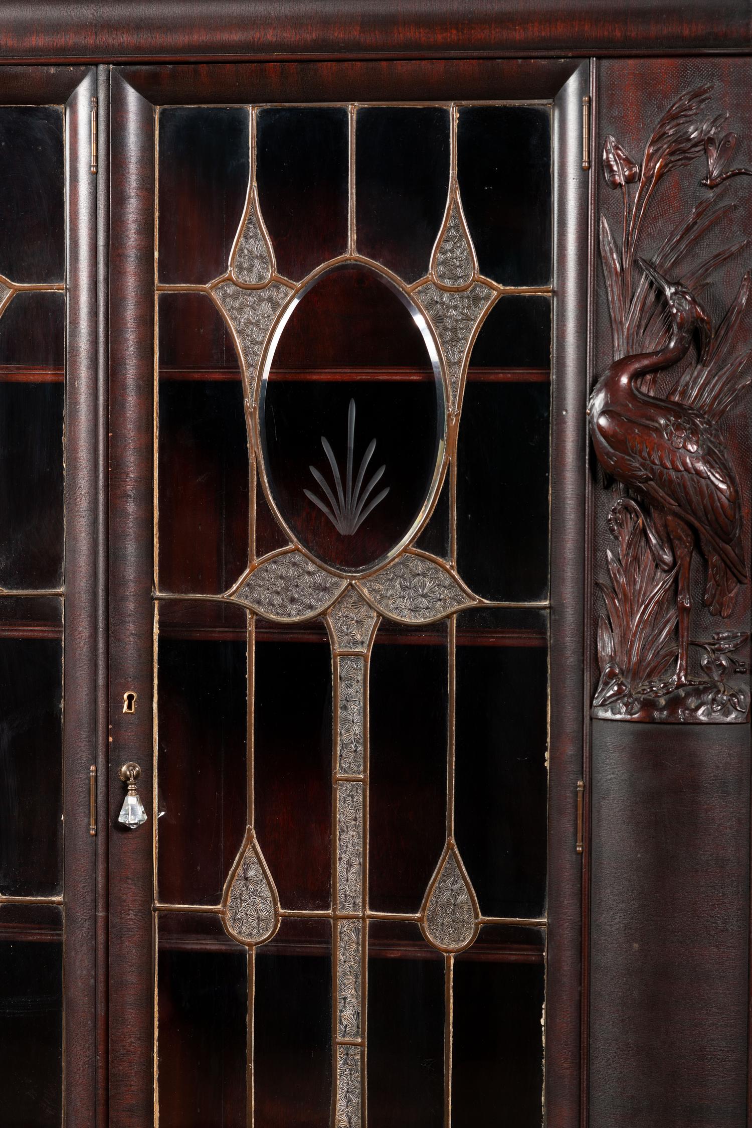 An Aesthetic Movement Crane and Mask Carved Mahogany and Glass Paneled Bookcase