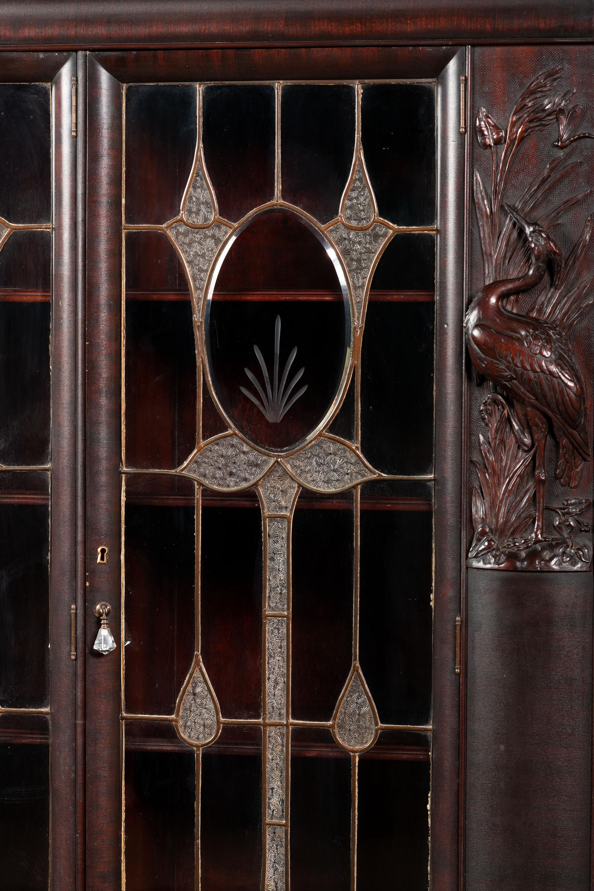 An Aesthetic Movement Crane and Mask Carved Mahogany and Glass Paneled Bookcase