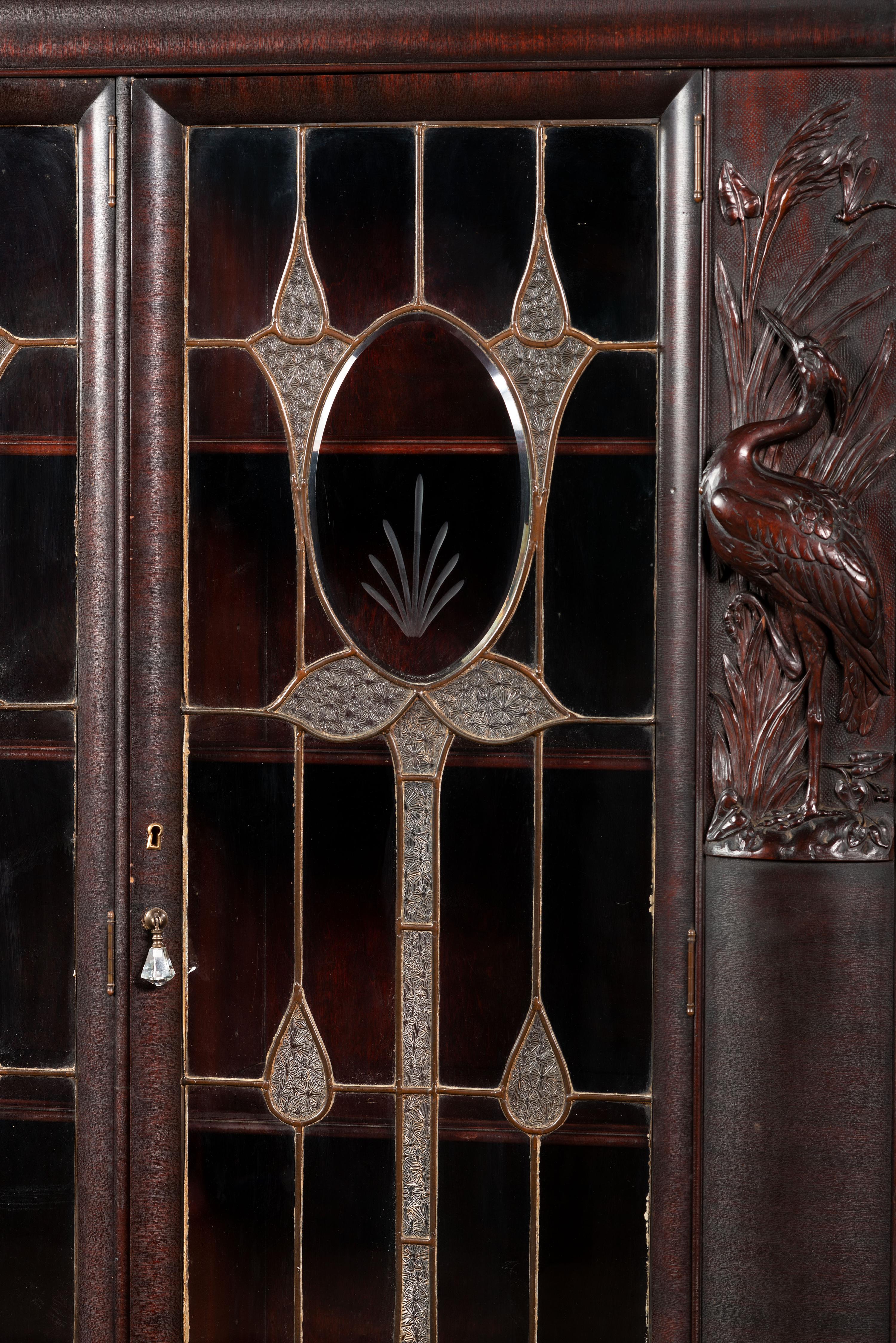 An Aesthetic Movement Crane and Mask Carved Mahogany and Glass Paneled Bookcase