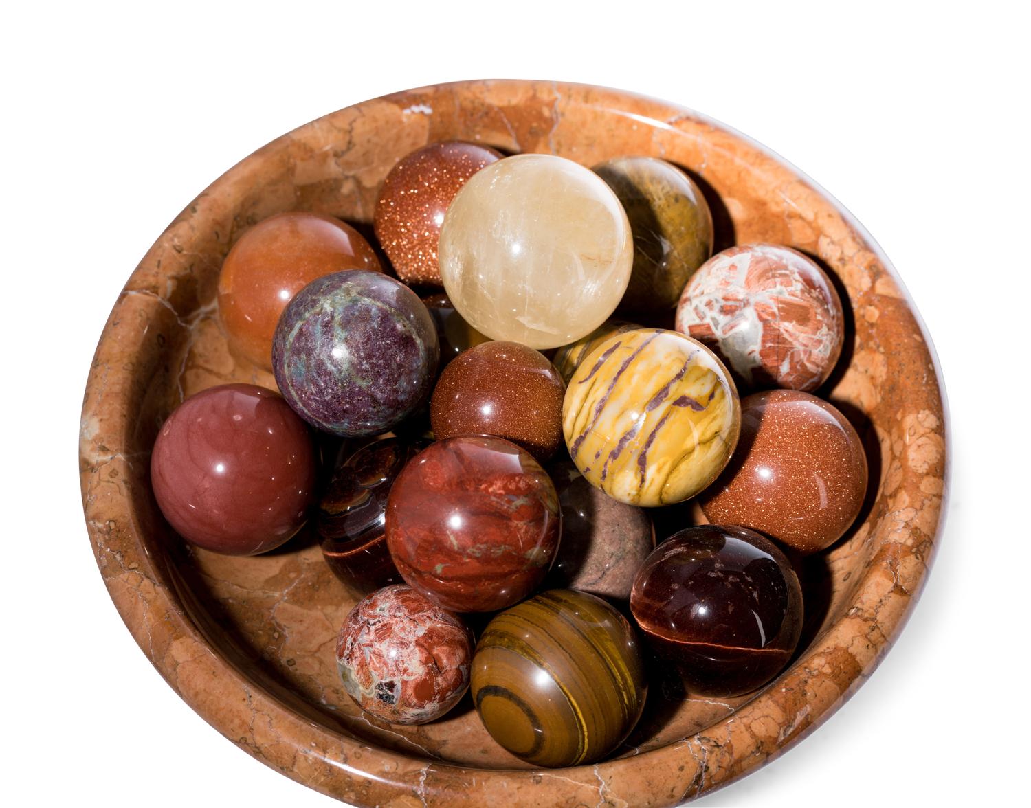 A Turned Marble Center Bowl with a Collection of Spherical Hardstone Ornaments