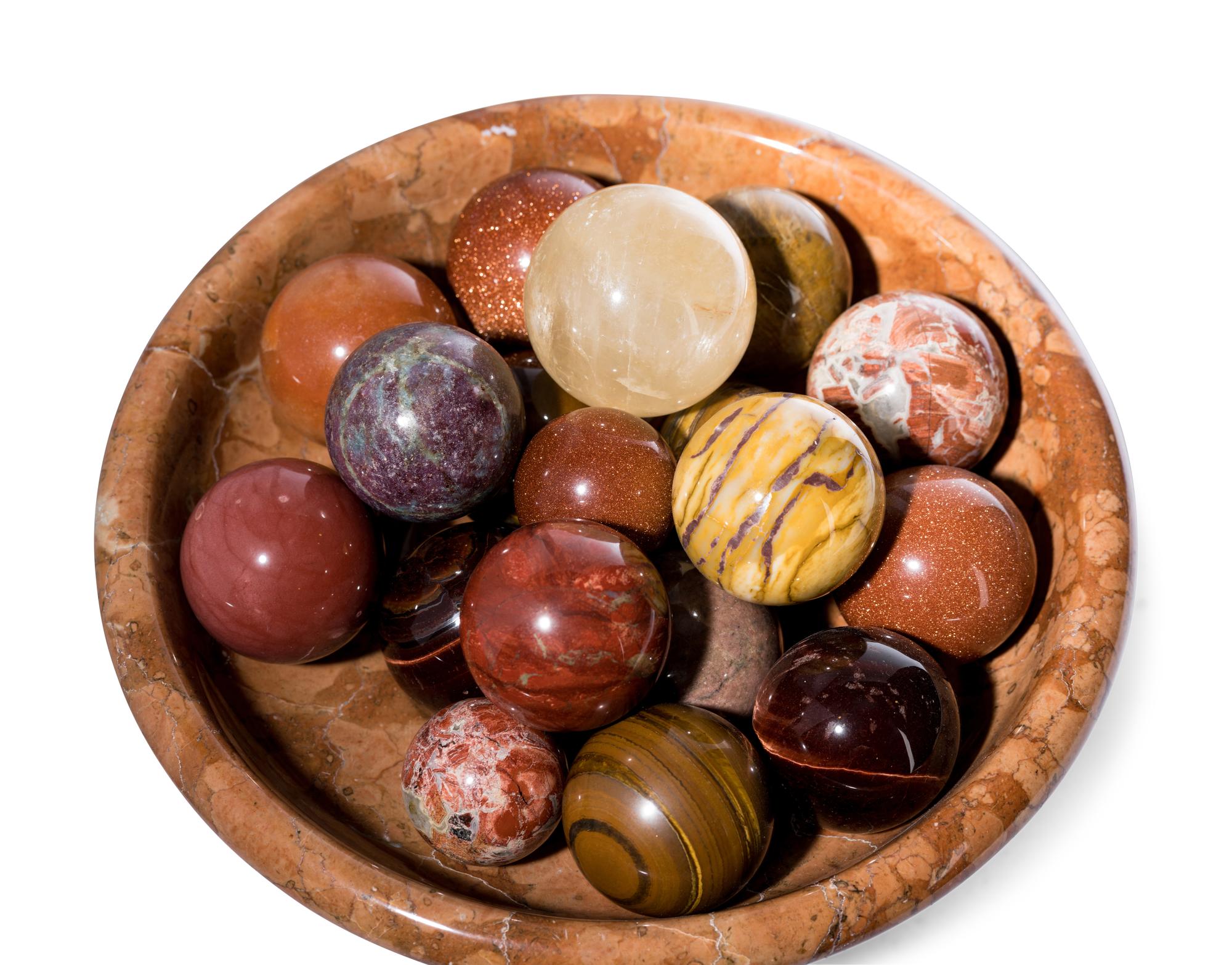 A Turned Marble Center Bowl with a Collection of Spherical Hardstone Ornaments
