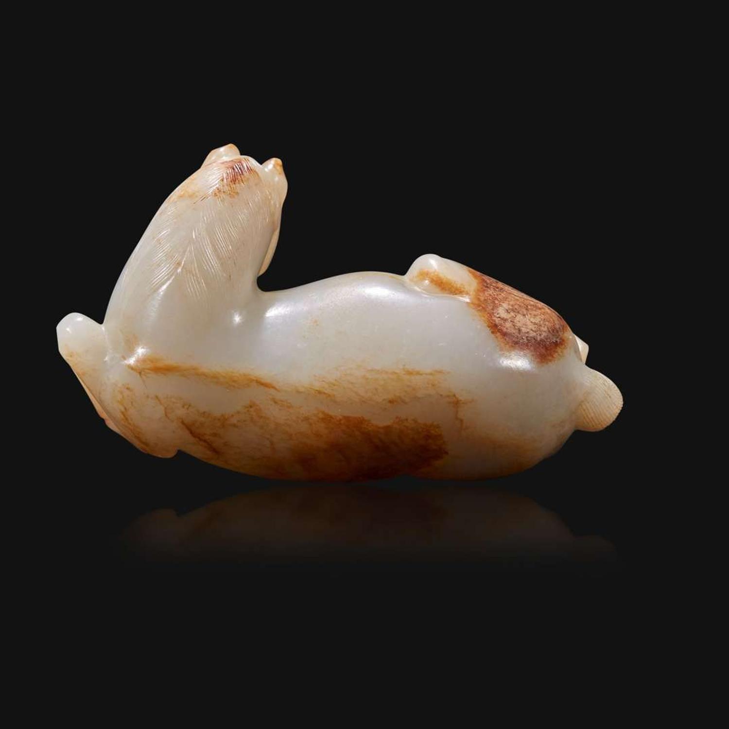 A Chinese russet and greyish-white carved jade figure of a recumbent horse