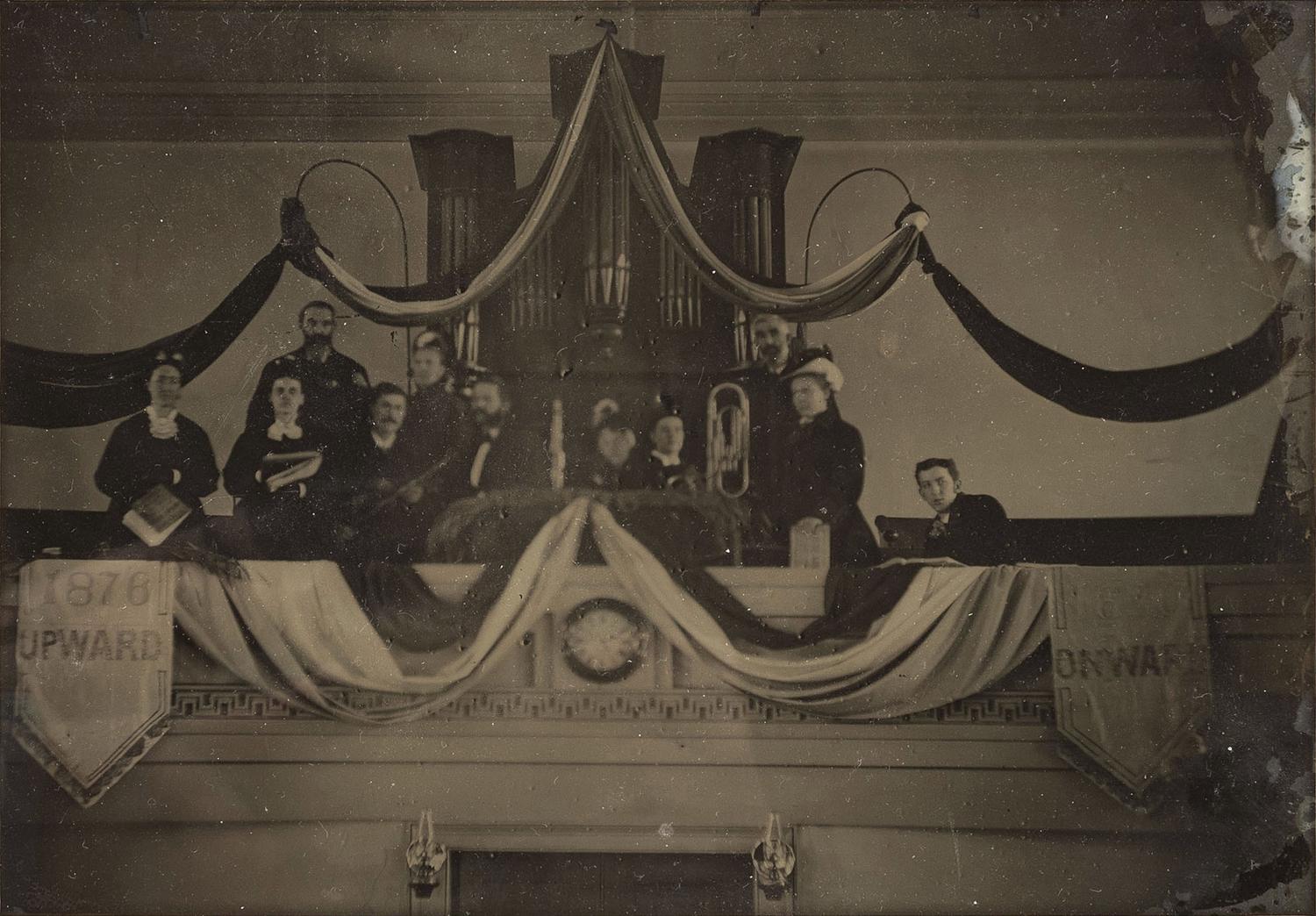 Ambrotypes Upward / Onward . Whole plate ambrotype of a musical group, likely a church band, posed in front of an organ. Ca 1876.