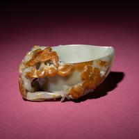 A Chinese Russet and Celadon Jade ‘Magpie and Plum Blossoms’ Peach-Form Coupe, 19th Century — 清晚期 青白玉帶皮喜上眉梢桃形杯