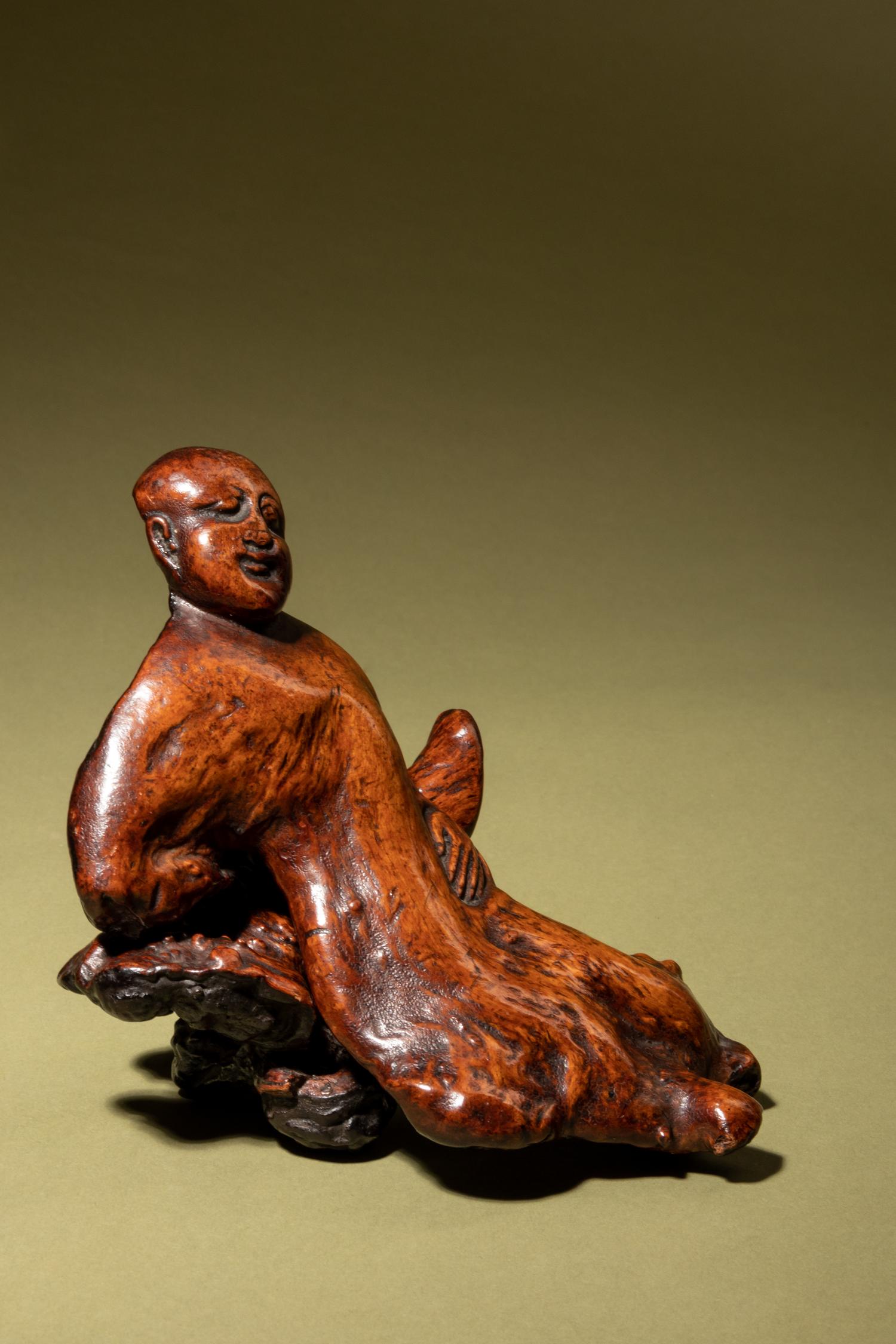 A Chinese Carved Root Figure of a Reclining Man and Stand