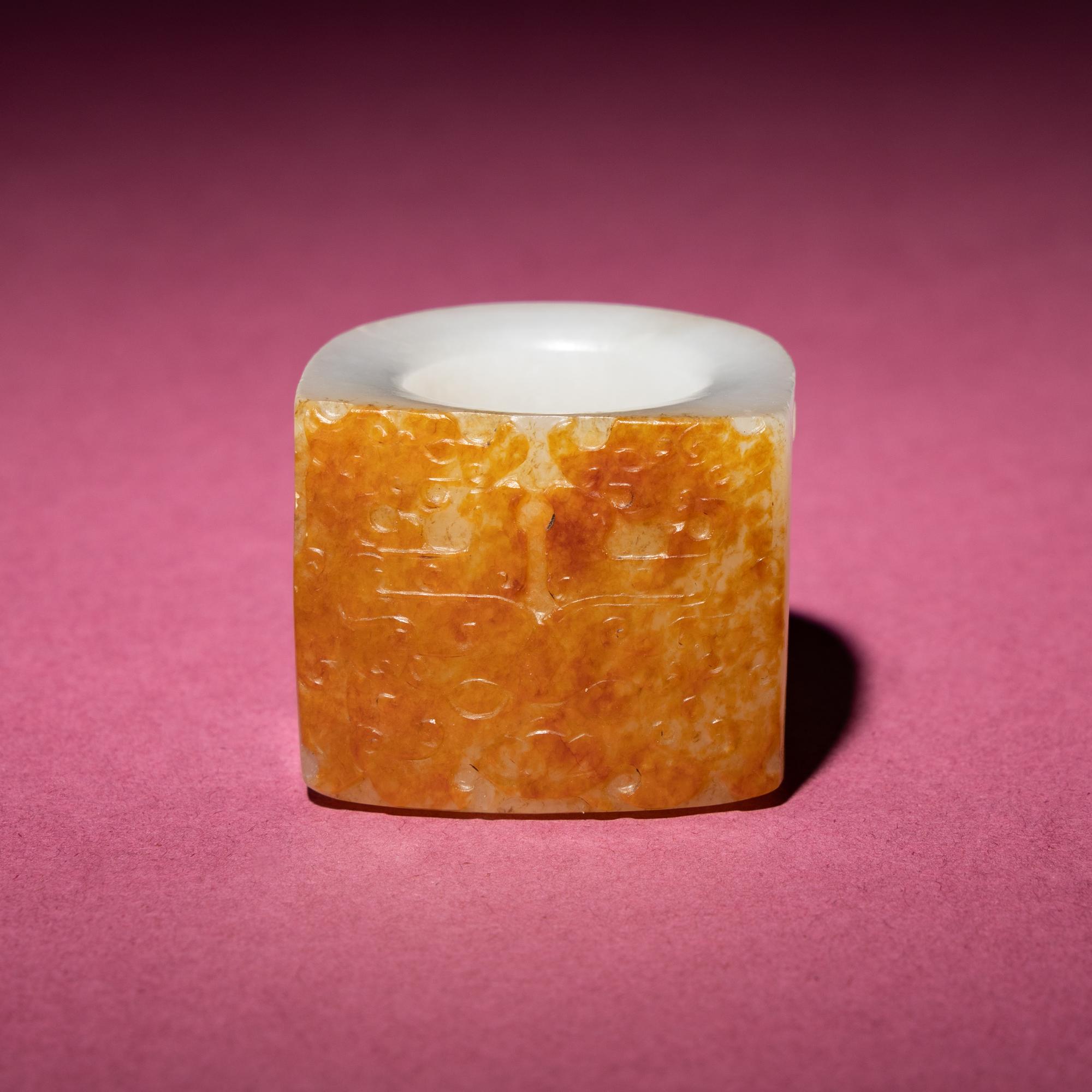 A Chinese Russet and White Jade 'Taotie and Chilong' Archer's Ring, 18th Century — 清中期 白玉留皮饕餮螭龍紋扳指
