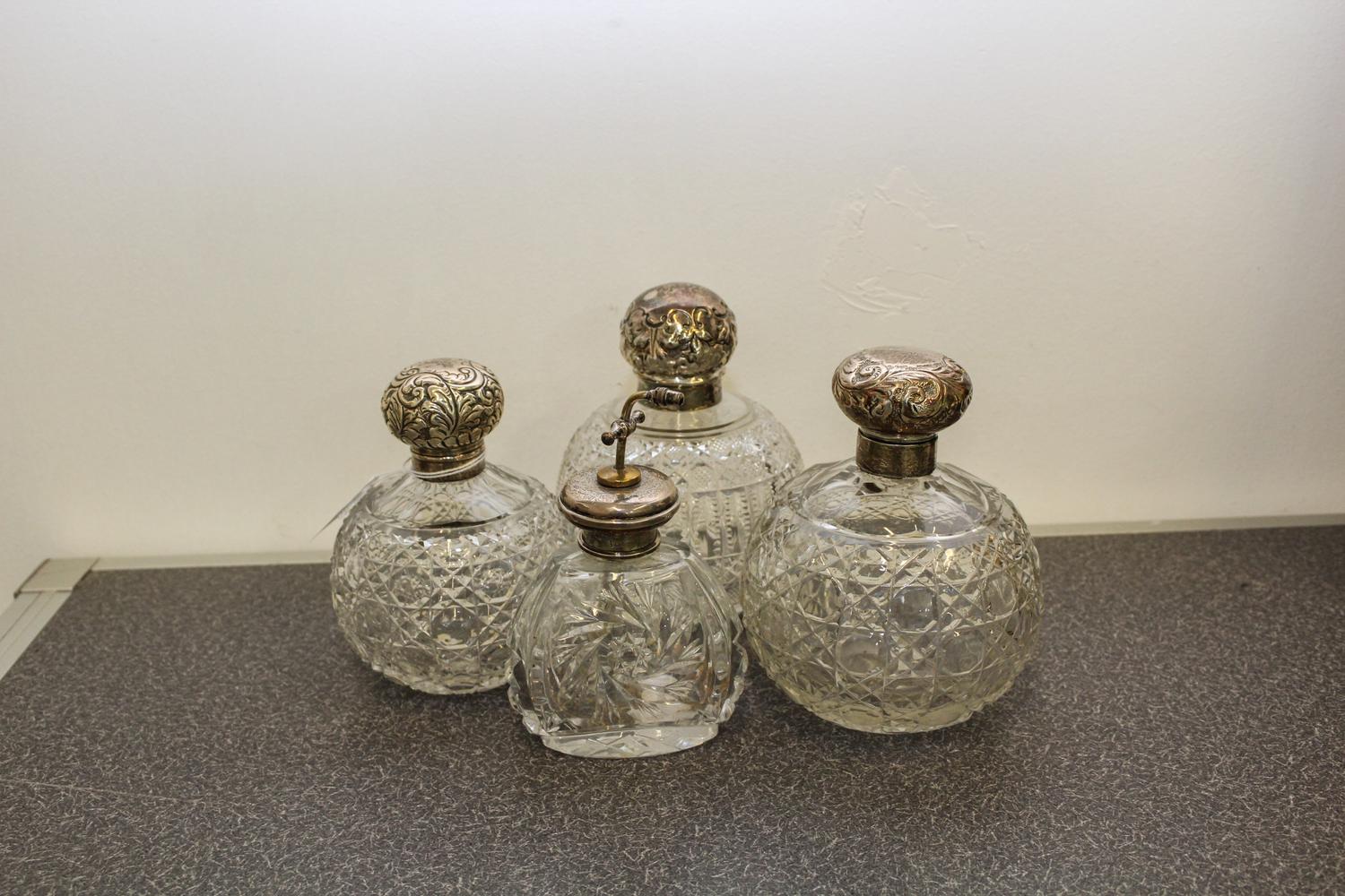 A Group of Three English Silver and Cut Glass Perfume Bottles, makers marks obscured, each having a spherical body worked with geometri