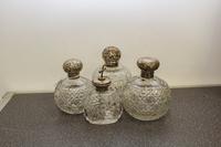 A Group of Three English Silver and Cut Glass Perfume Bottles, makers marks obscured, each having a spherical body worked with geometri