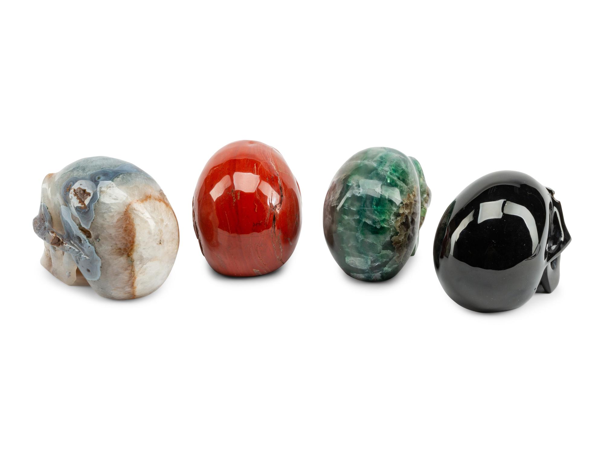 A Set of Four Carved Agate, Fluorite, Red Jasper and Black Obsidian Skulls