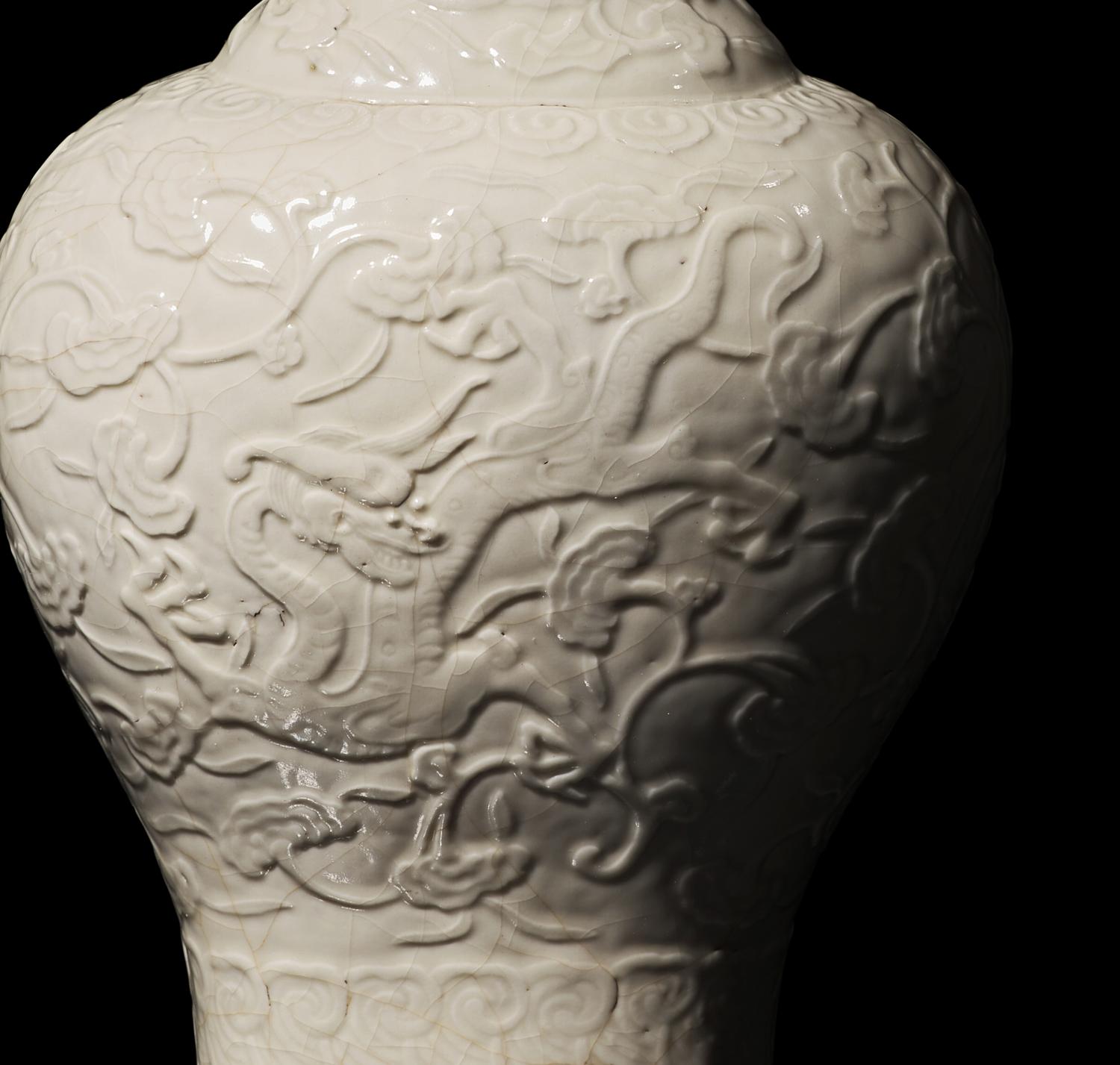 A Chinese White Glazed Soft Paste Molded 'Dragons and Lingzhi' Vase, 18th Century 清中期 白釉模印漿胎靈芝螭龍紋瓶