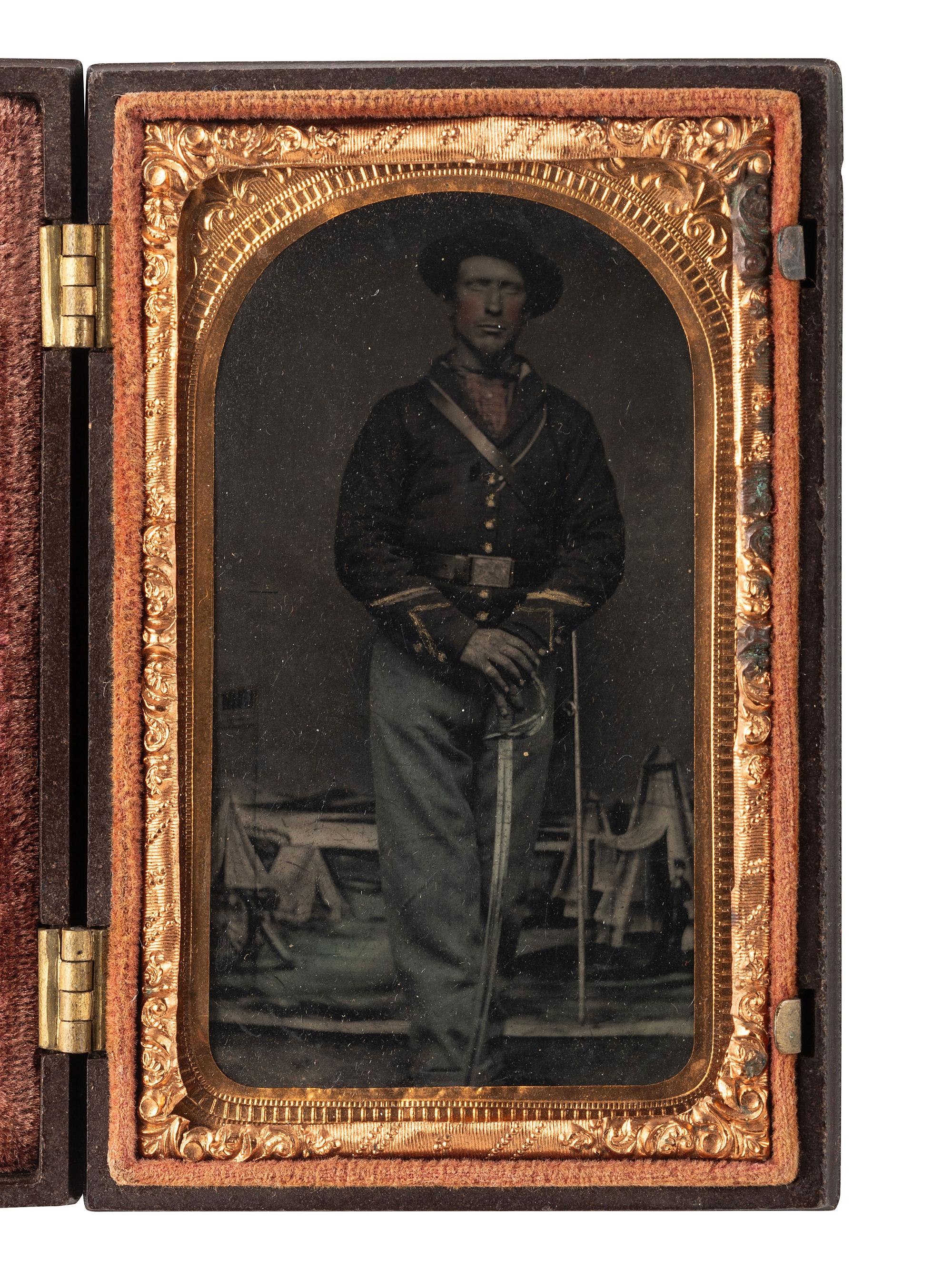 [CIVIL WAR]. CDV-sized tintype of a Union cavalryman posed against a military camp background.