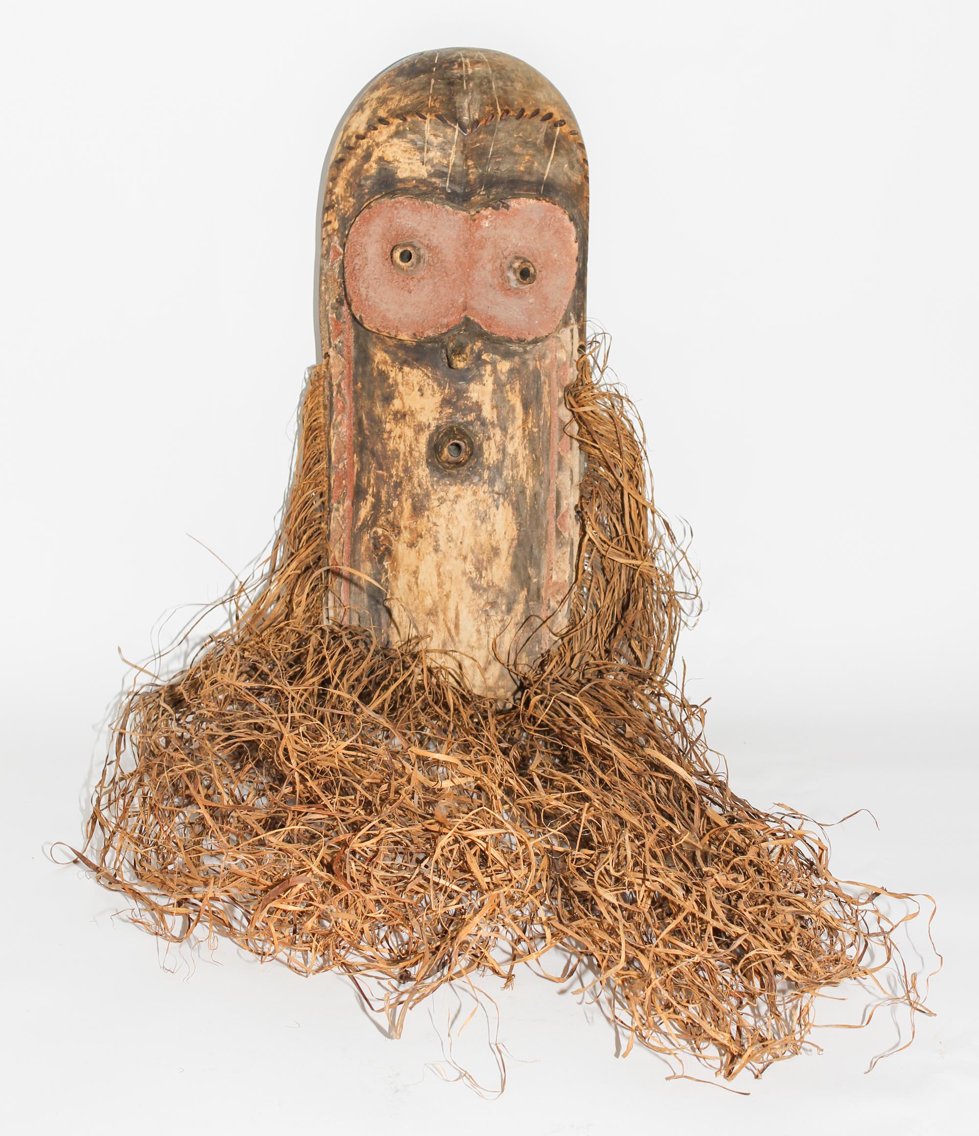 A Wabembe Wood and Grass Fiber Mask. Height 18 inches (without grass).