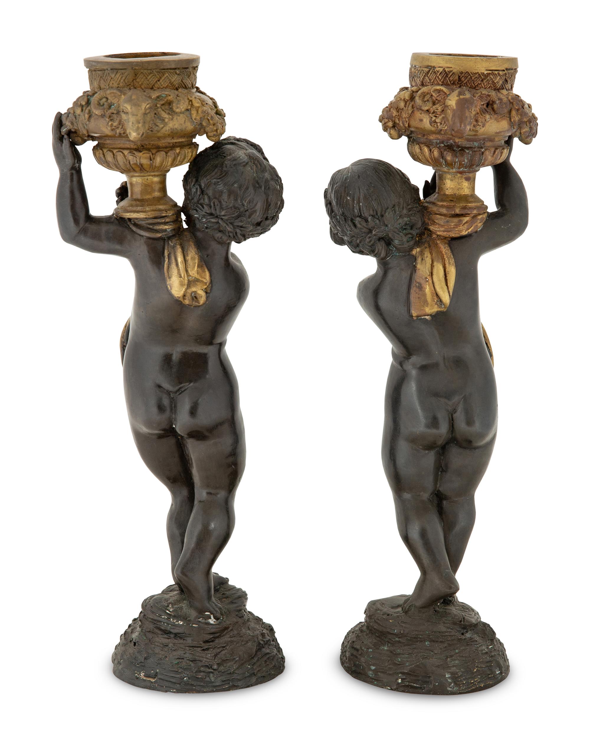 A Pair of Parcel Gilt Cast Metal Putti Candlesticks
